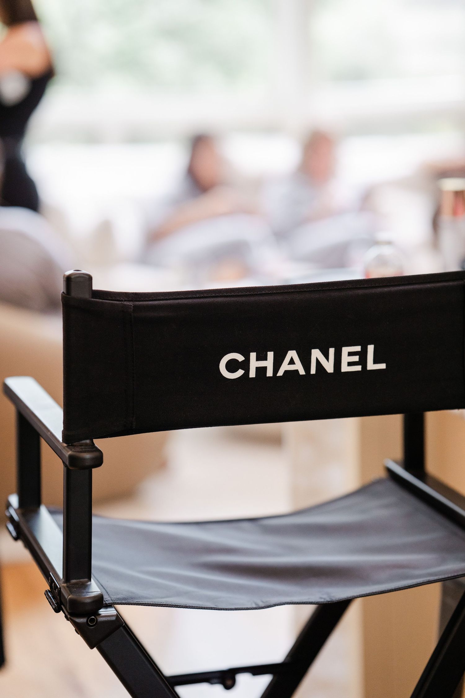 Elegant black Chanel director chair in a bright, softly blurred event space.