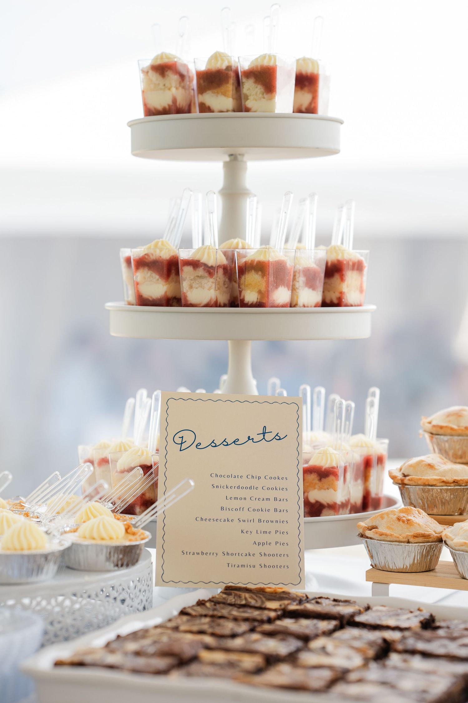 Tiered dessert display with cheesecake cups, brownies, and mini pies at a wedding reception.