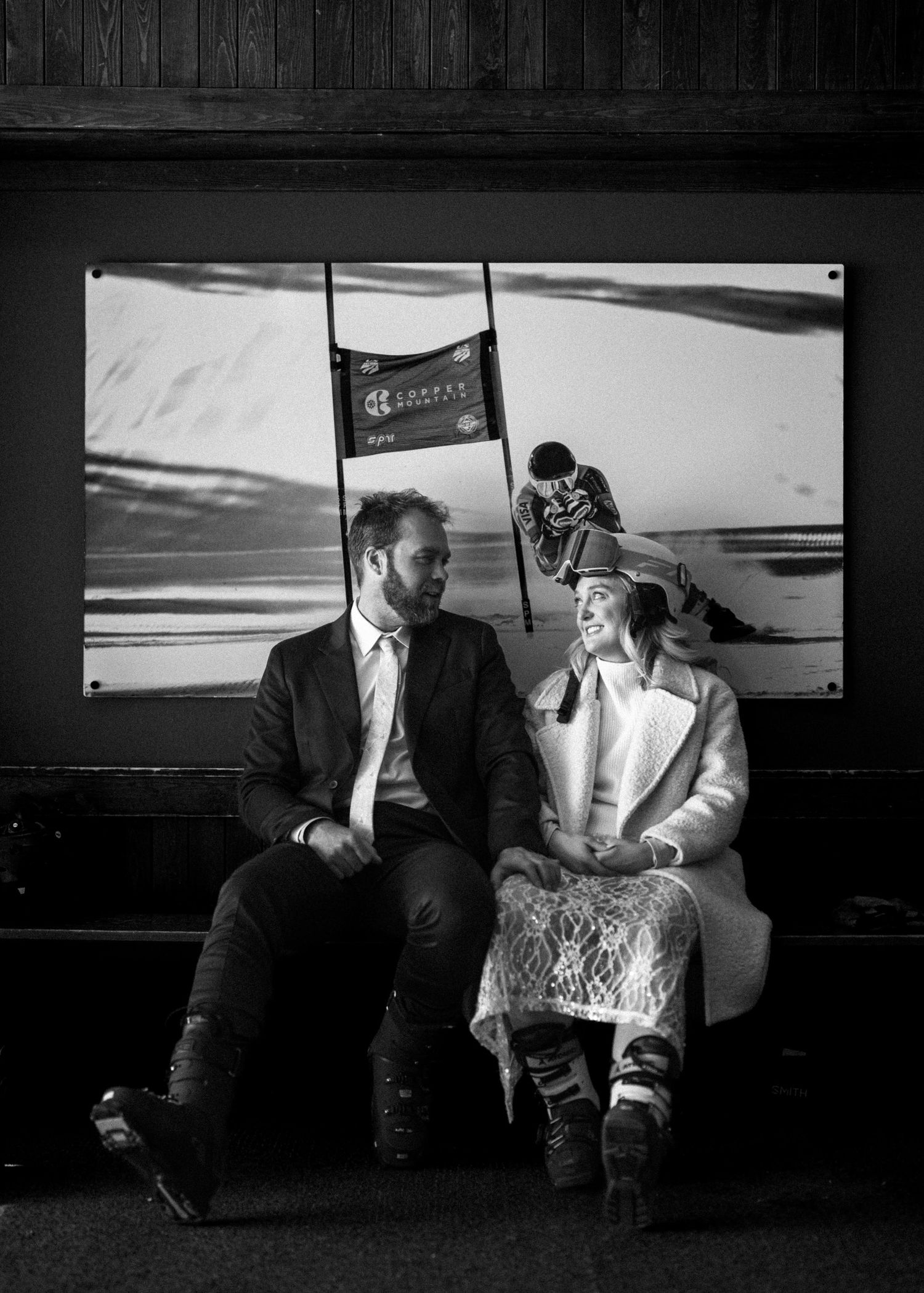 Couple sitting together in a ski lodge with a skiing action photo on the wall.