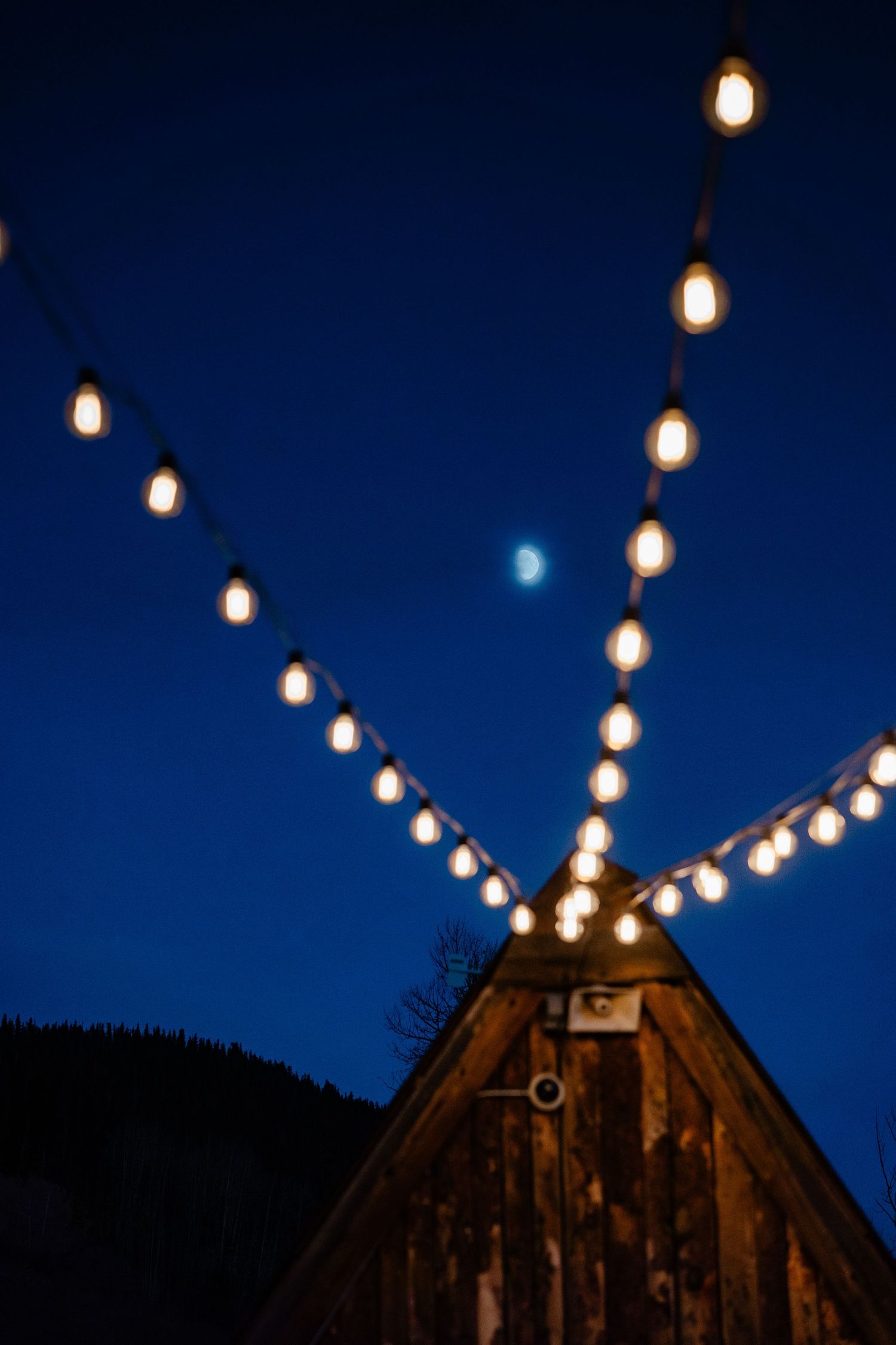 String lights glowing against deep blue night sky above rustic wooden barn.
