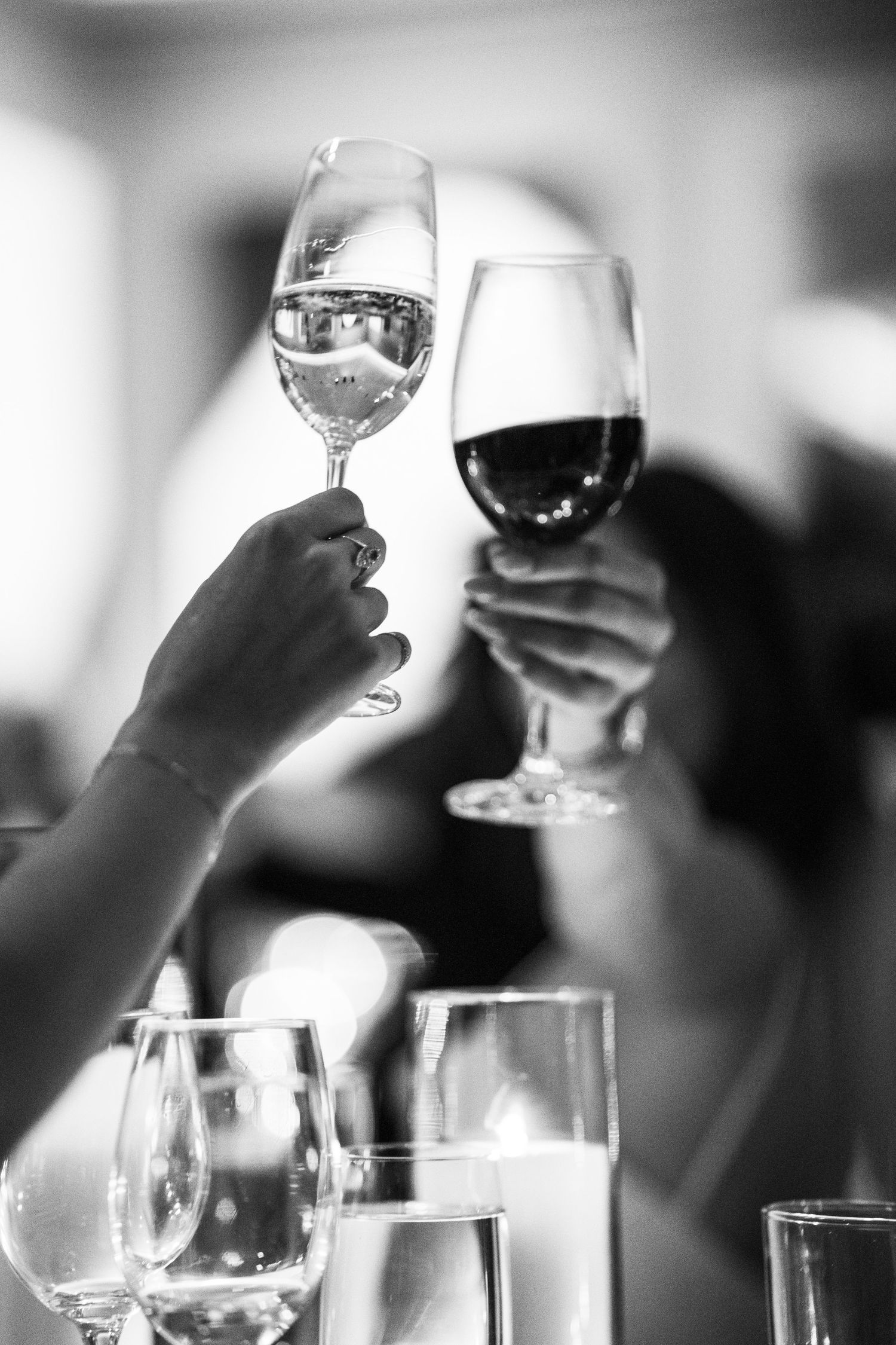 Two guests clink wine glasses in a black and white wedding reception toast photo.