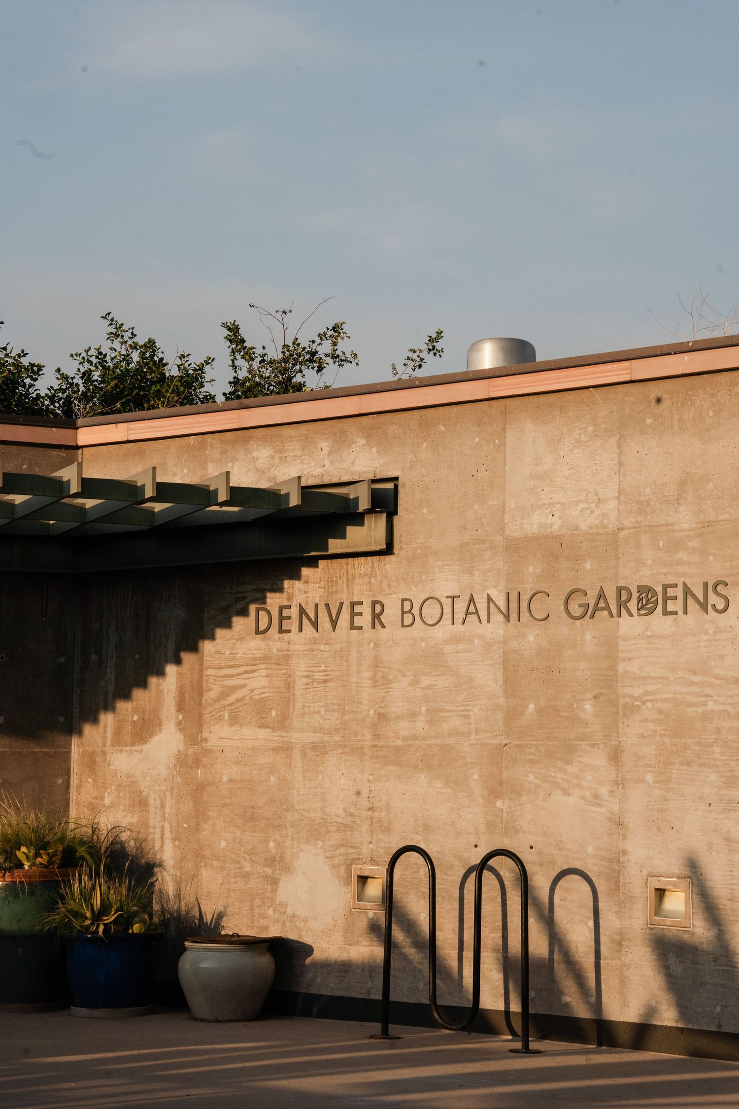Exterior wall of Denver Botanic Gardens building at golden hour with bike rack.