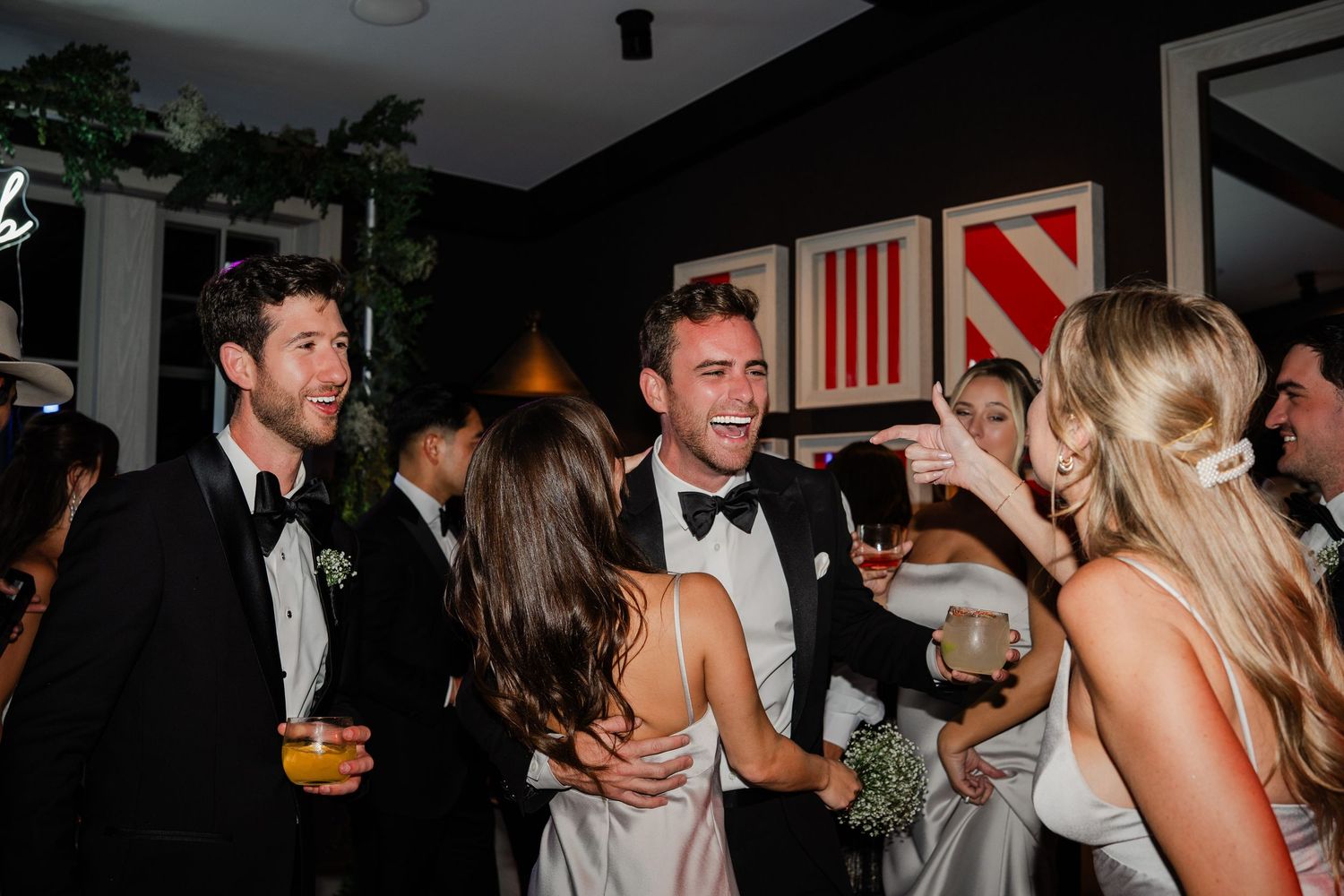 Guests in formal attire socializing and laughing at an elegant wedding reception party.