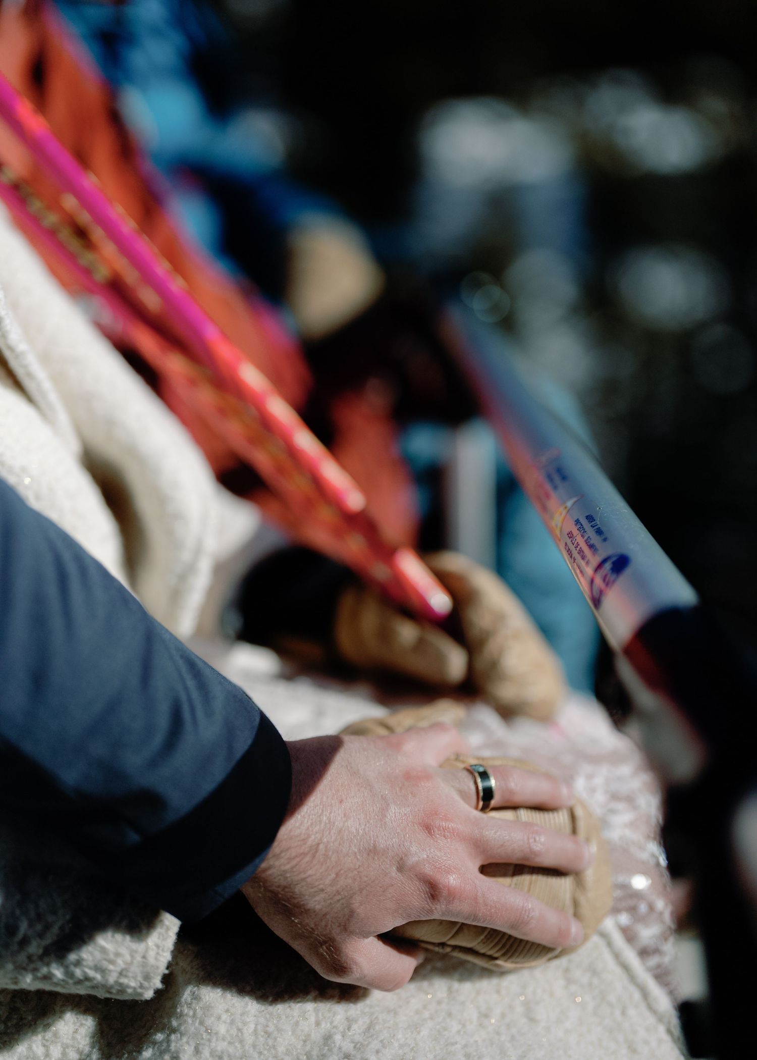 Close-up of newlyweds holding hands with wedding rings visible at a ski resort.