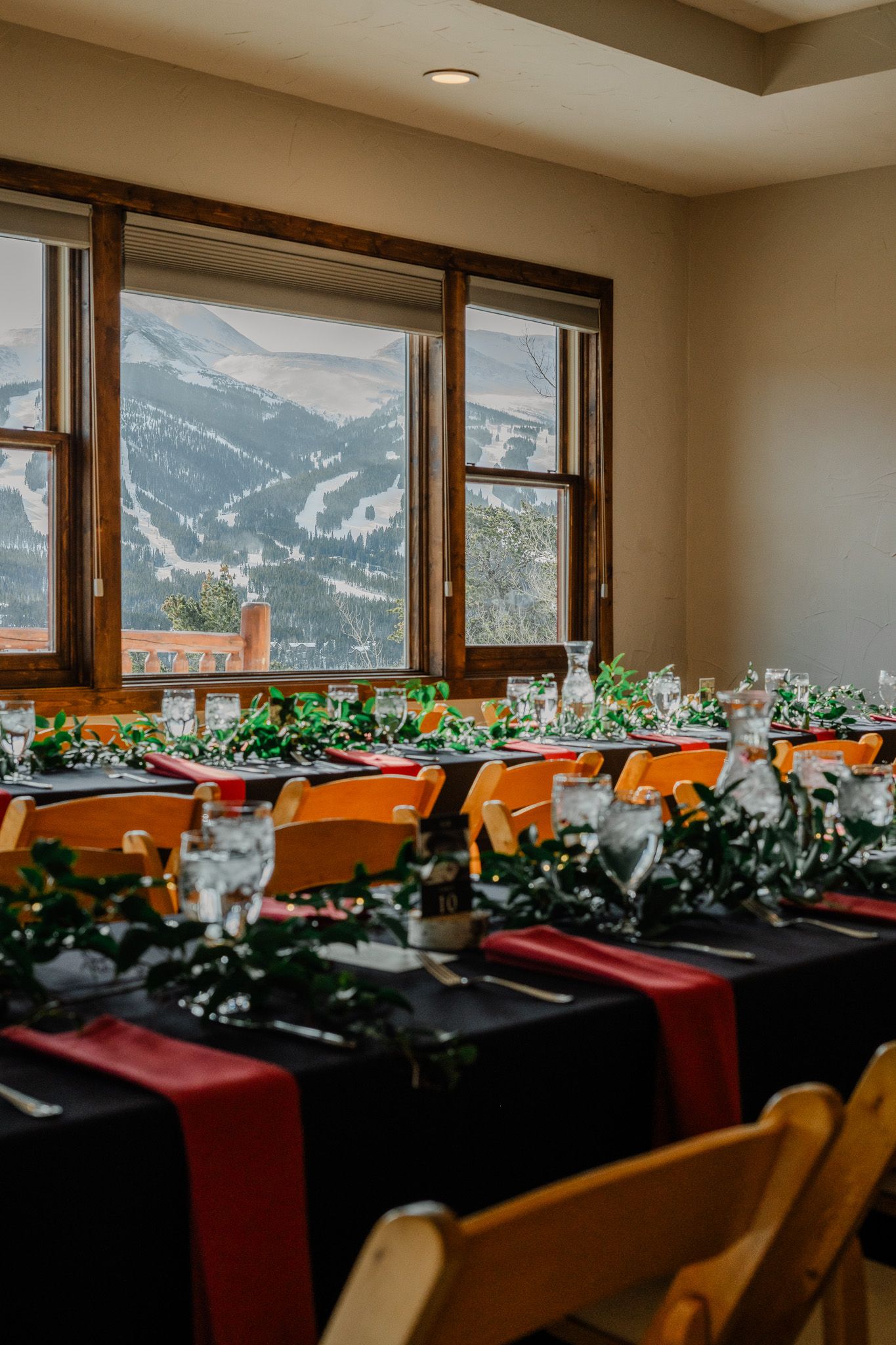 Elegant wedding reception table with black linens, red runners, and snowy mountain views.