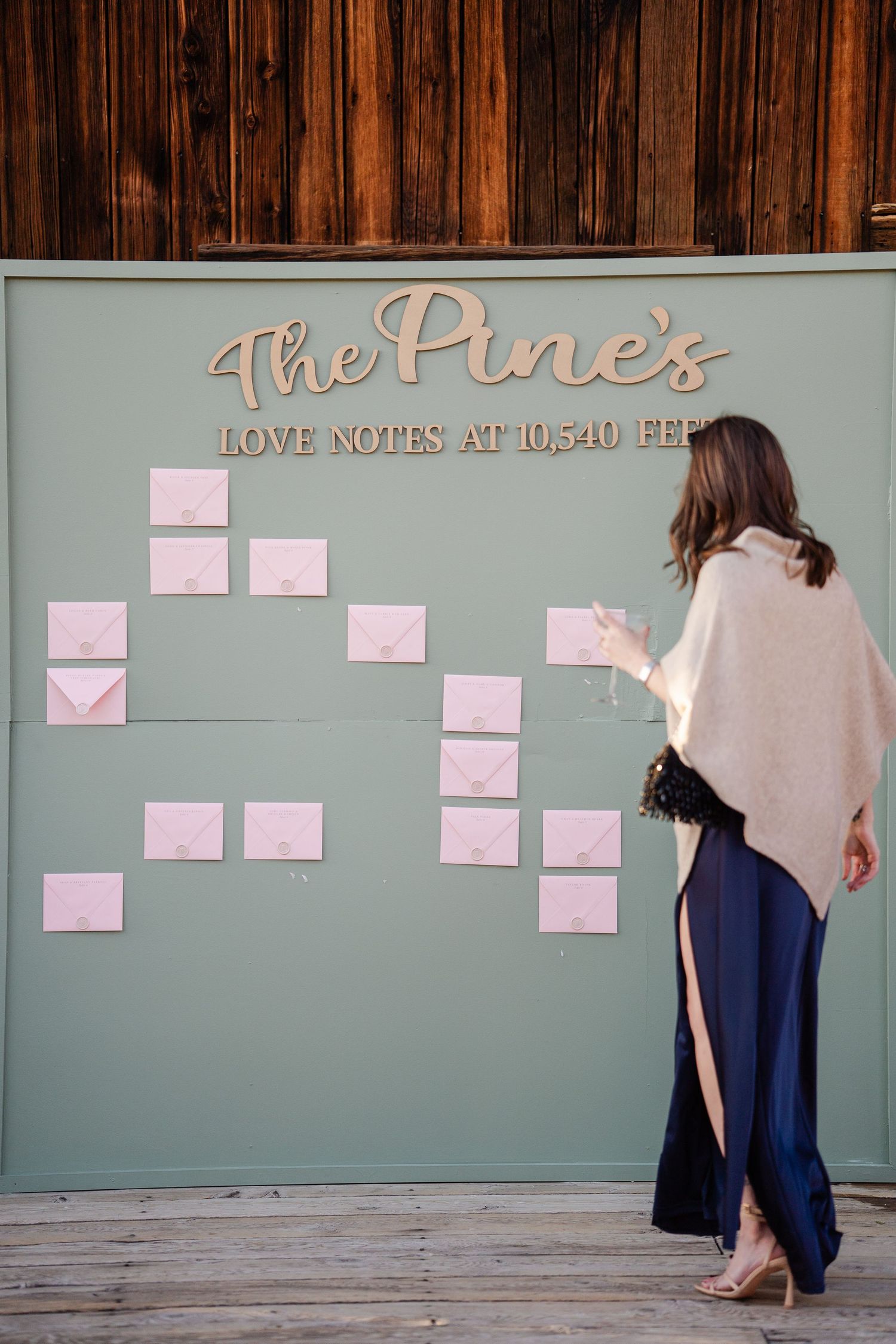 Woman in navy skirt views pink envelope love notes wall at The Pines wedding venue.
