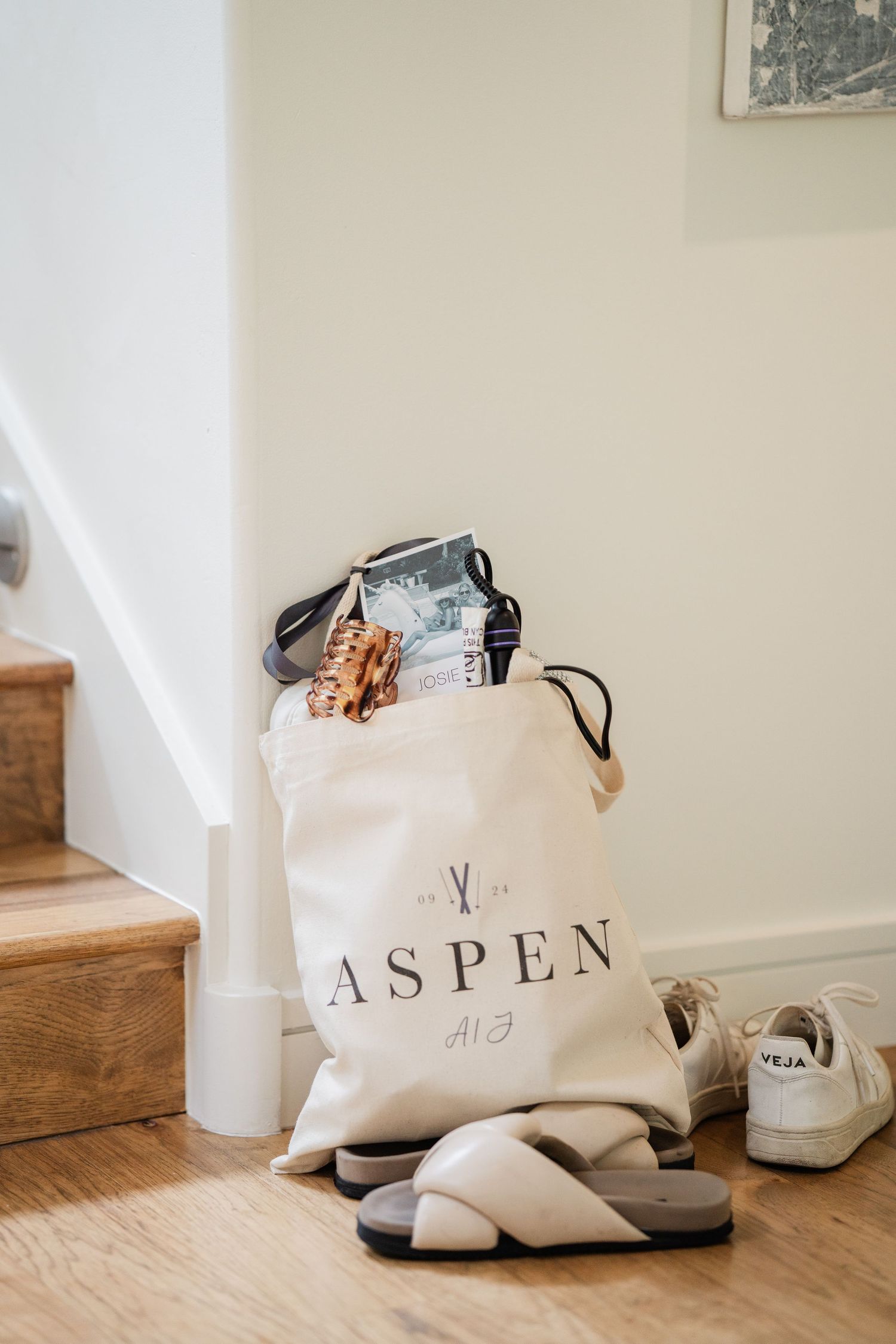 Canvas tote bag printed with Aspen logo filled with wedding welcome gifts on stairs.