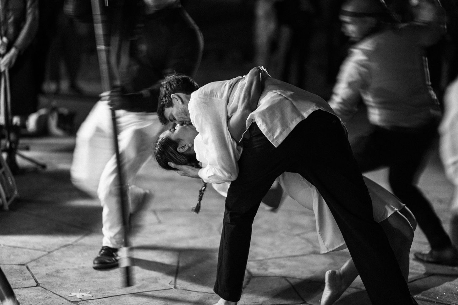 Black and white photo of couple sharing romantic dip kiss on dance floor during wedding reception.