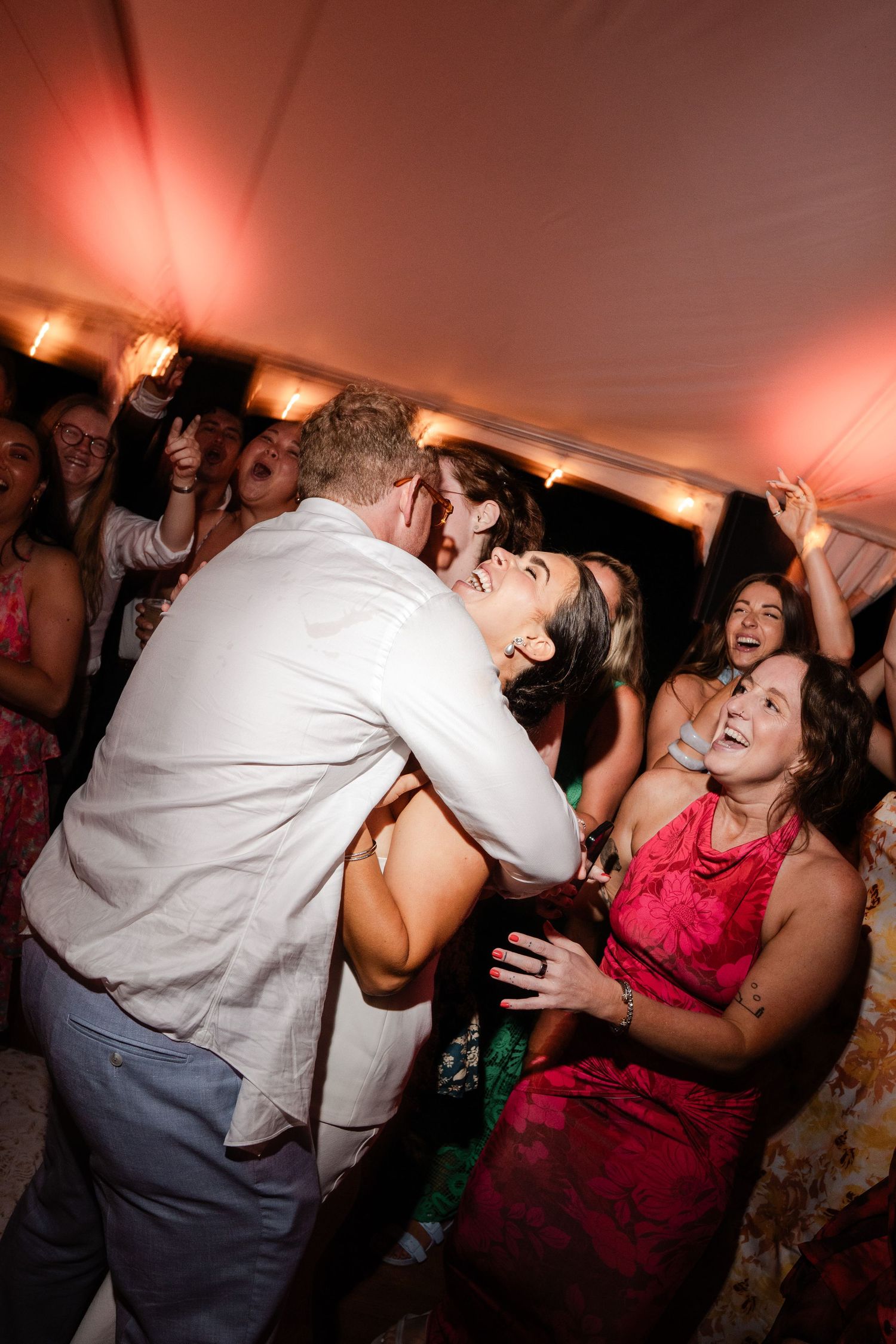 Bride and groom share a joyful dance surrounded by cheering guests at their reception.