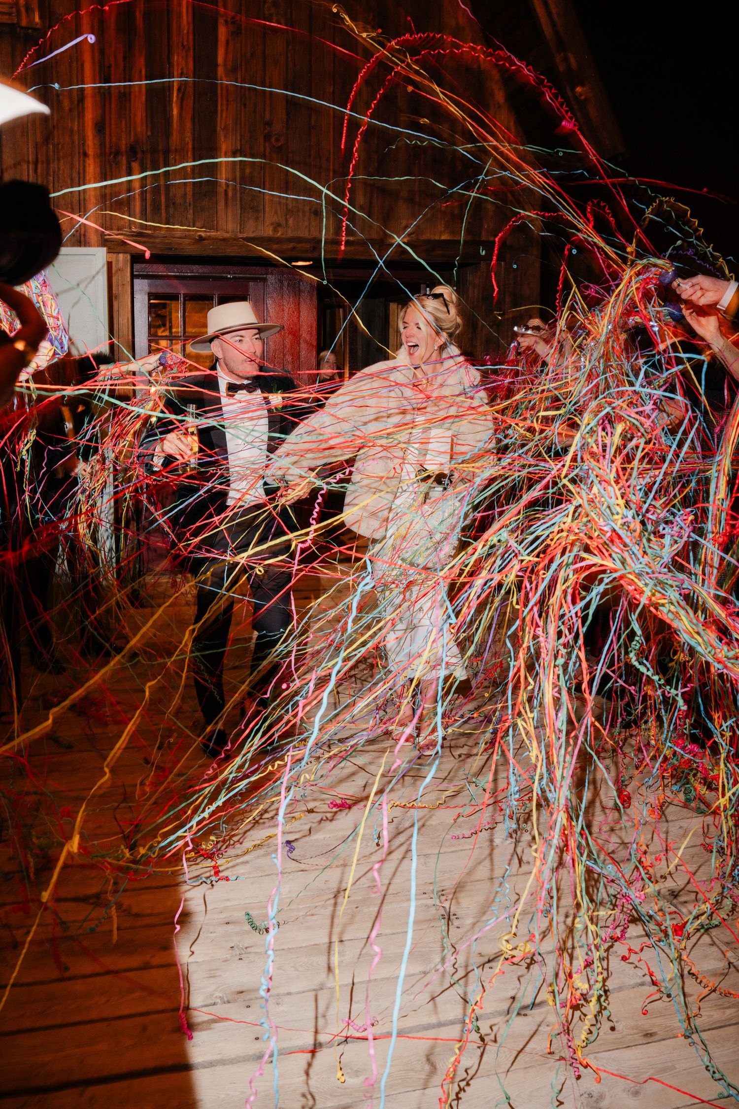 Bride and groom surrounded by colorful streamers during wedding sendoff.