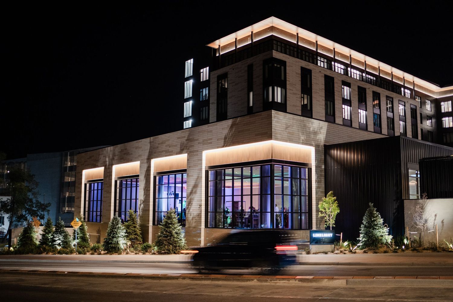 Modern hotel or event venue exterior illuminated at night with warm architectural lighting.
