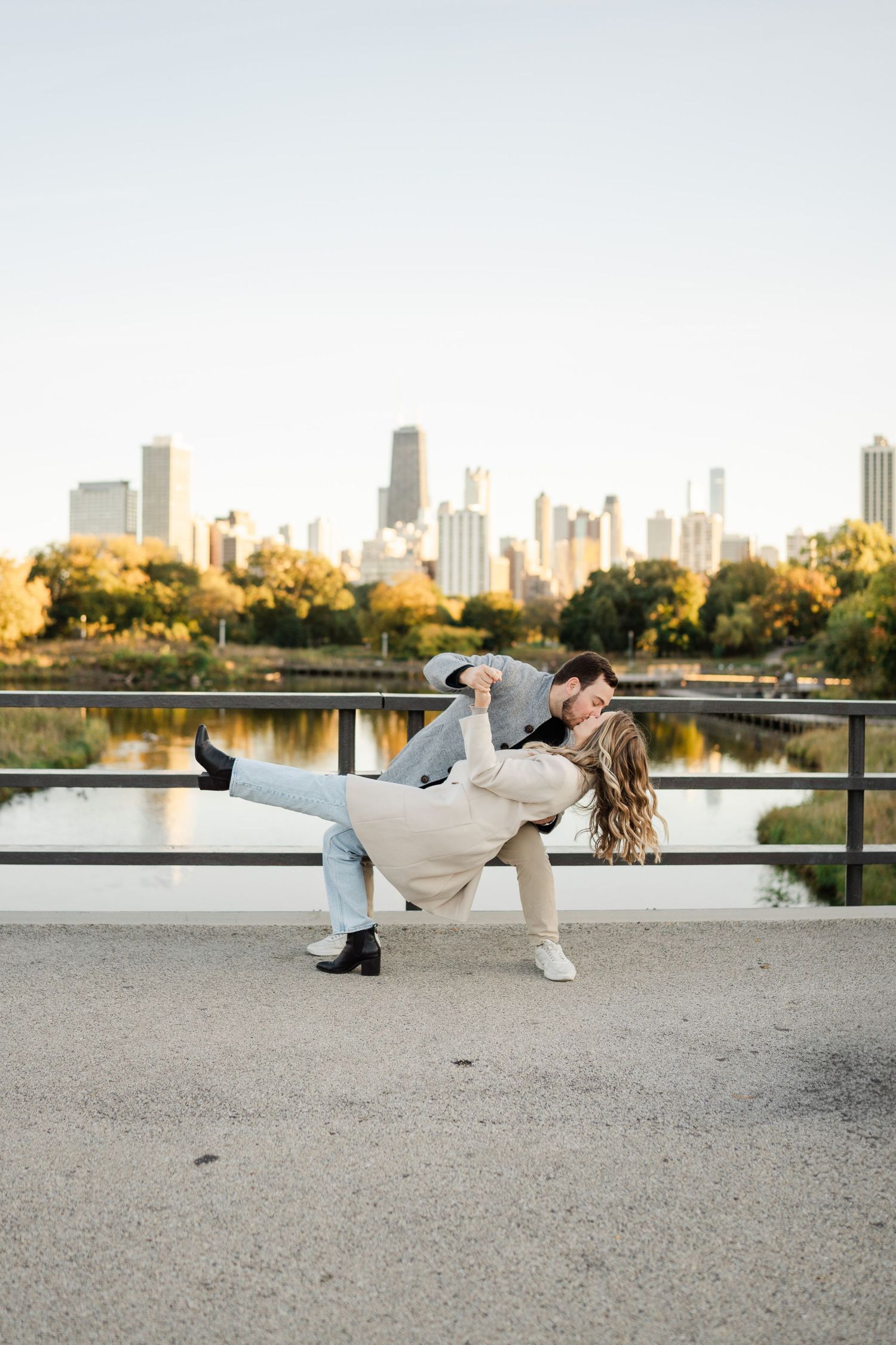 Romantic couple sharing a dip kiss with the Chicago city skyline and park in the background.