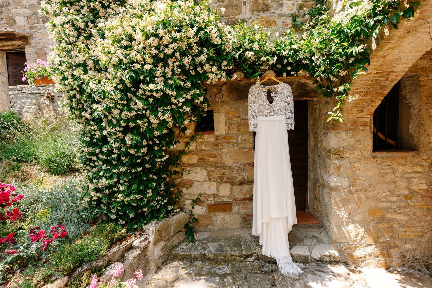 A rustic stone wall adorned with climbing vines and flowers creates a romantic Mediterranean garden atmosphere.