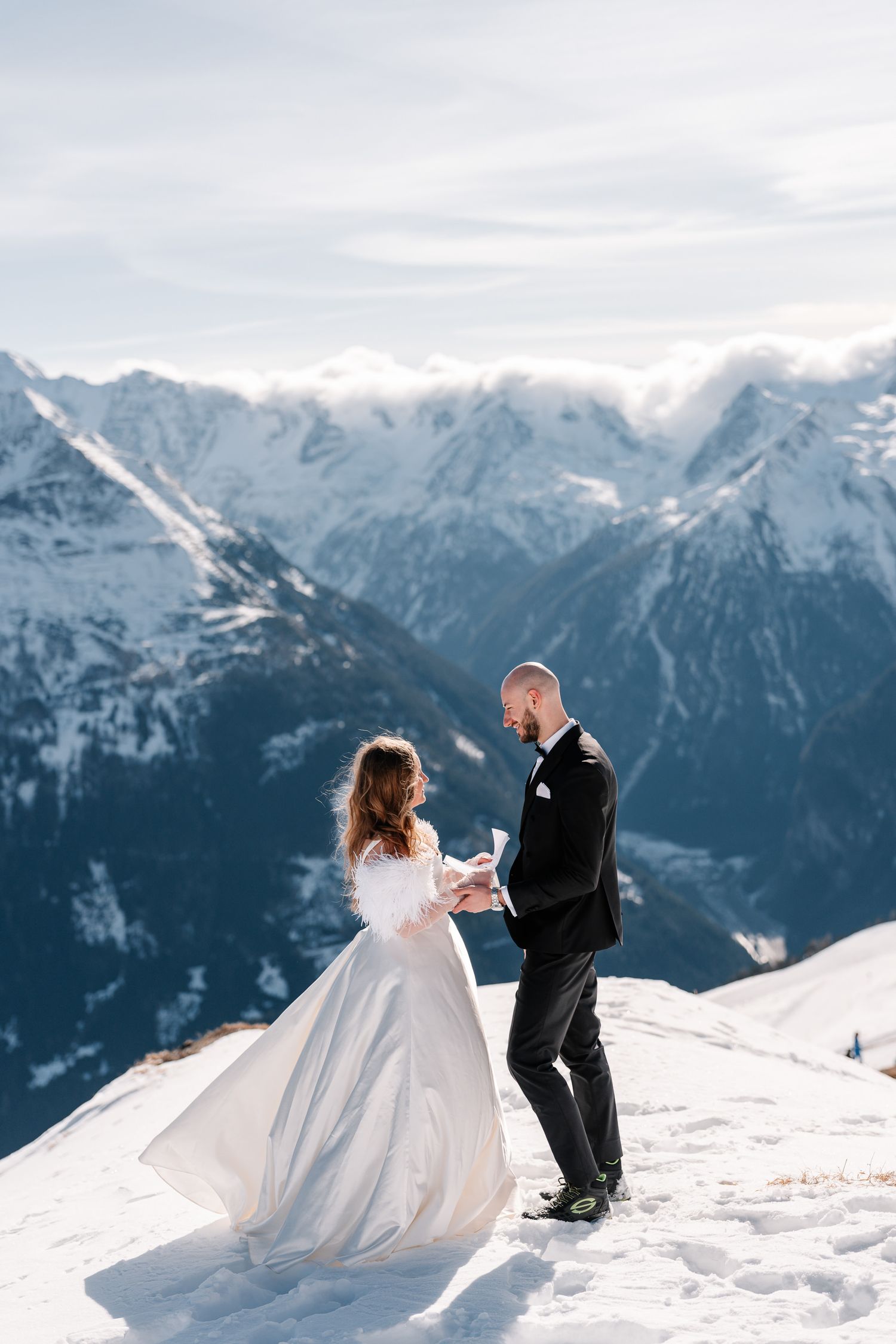 A couple shares an intimate moment during their winter mountain wedding photoshoot against snowy alpine peaks.