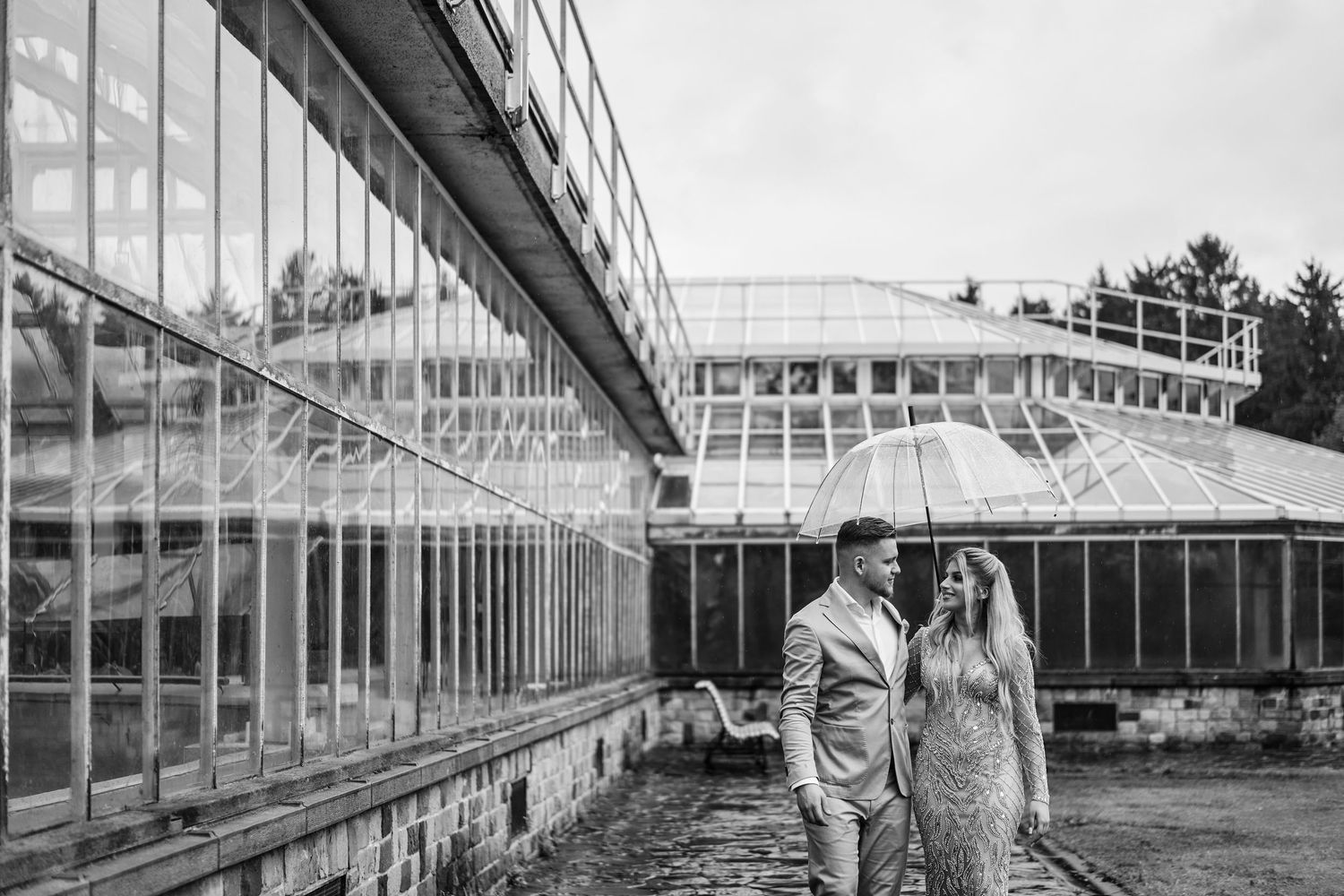 Historic greenhouse interior with glass panels and metal framework stretches into the distance at Longwood Gardens.