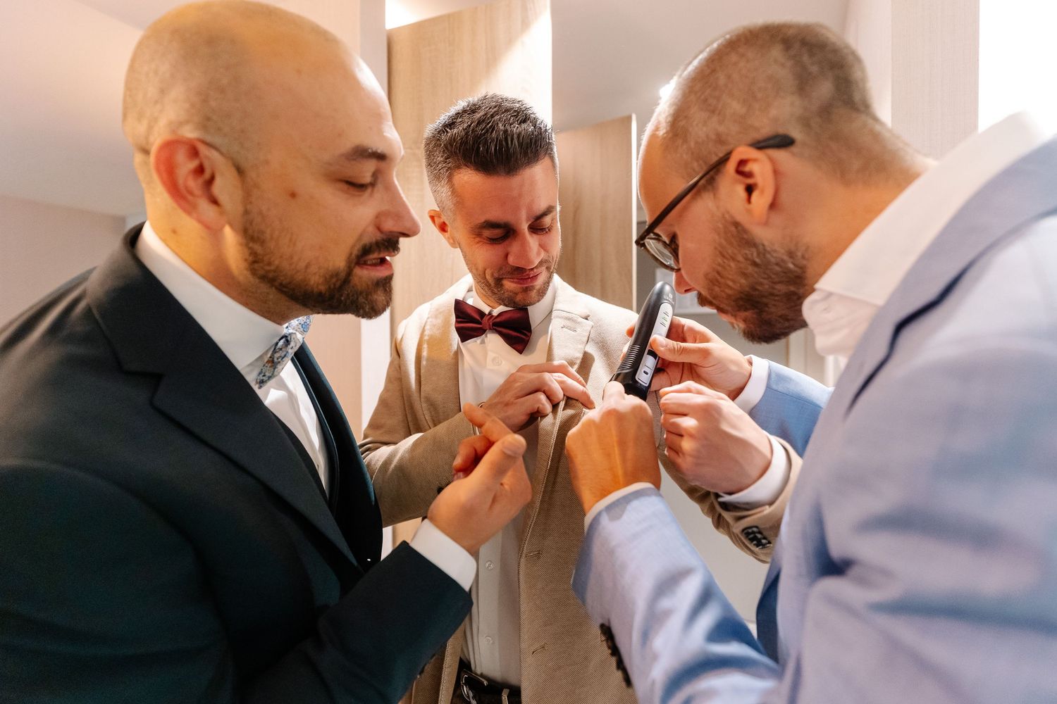 Groomsmen sharing emotional moments and helping each other prepare before wedding ceremony.
