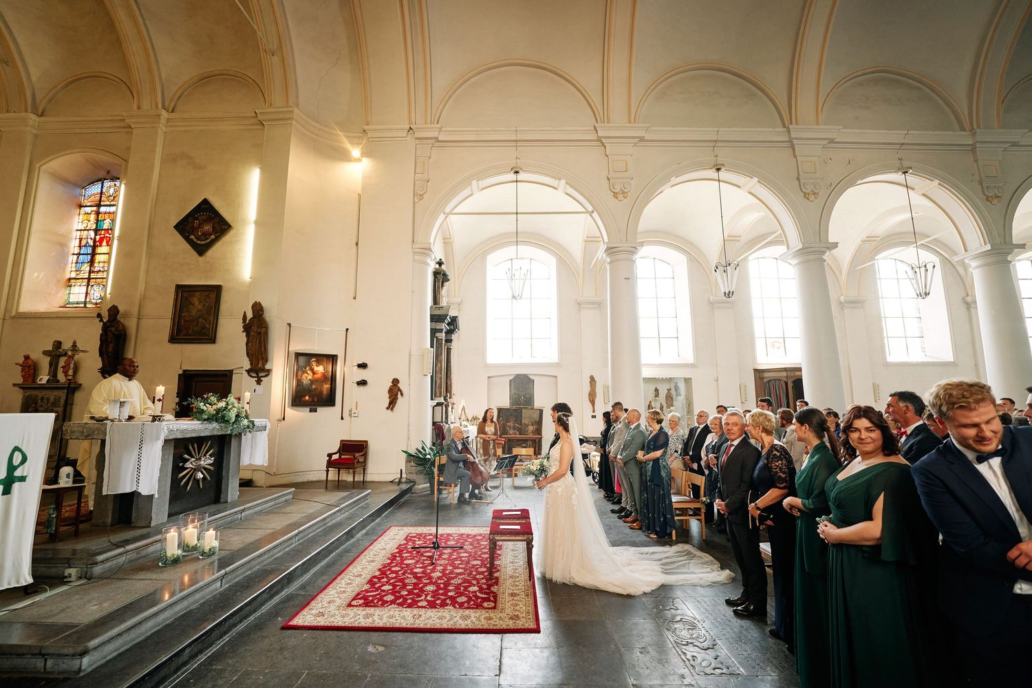 A panoramic view of guests gathered inside a grand church interior with white walls and arched ceilings.