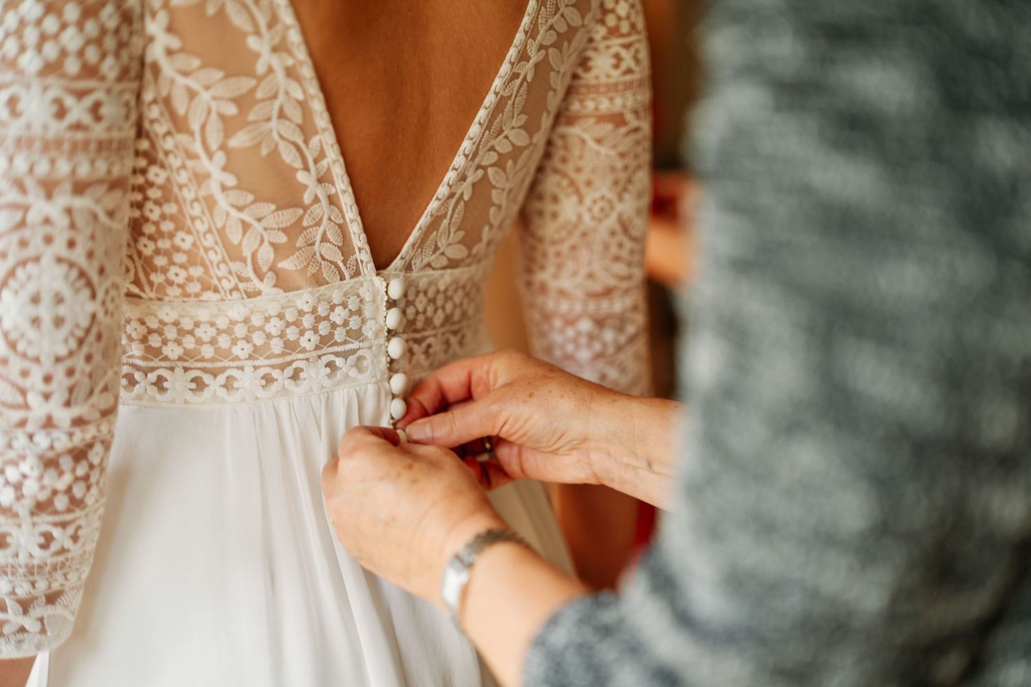 Close-up details of intricate lace wedding dress with beaded embellishments and delicate patterns.