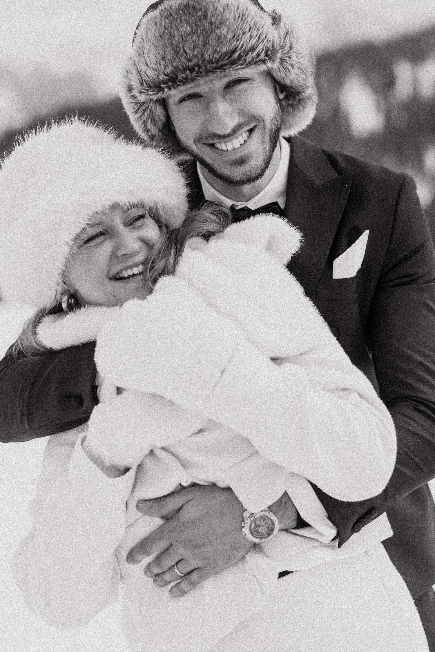 A romantic black and white photo series showing a couple embracing in winter fur hats and coats.