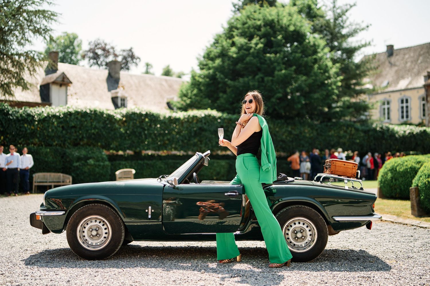 A vintage black sports car parked on a gravel driveway showcases its classic design and elegant profile.