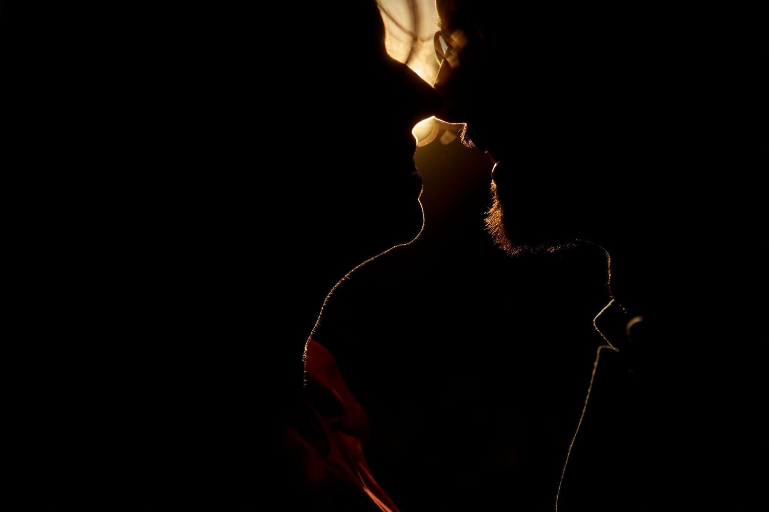 A silhouetted figure stands in dramatic lighting against a dark background with warm rim light highlighting their outline.