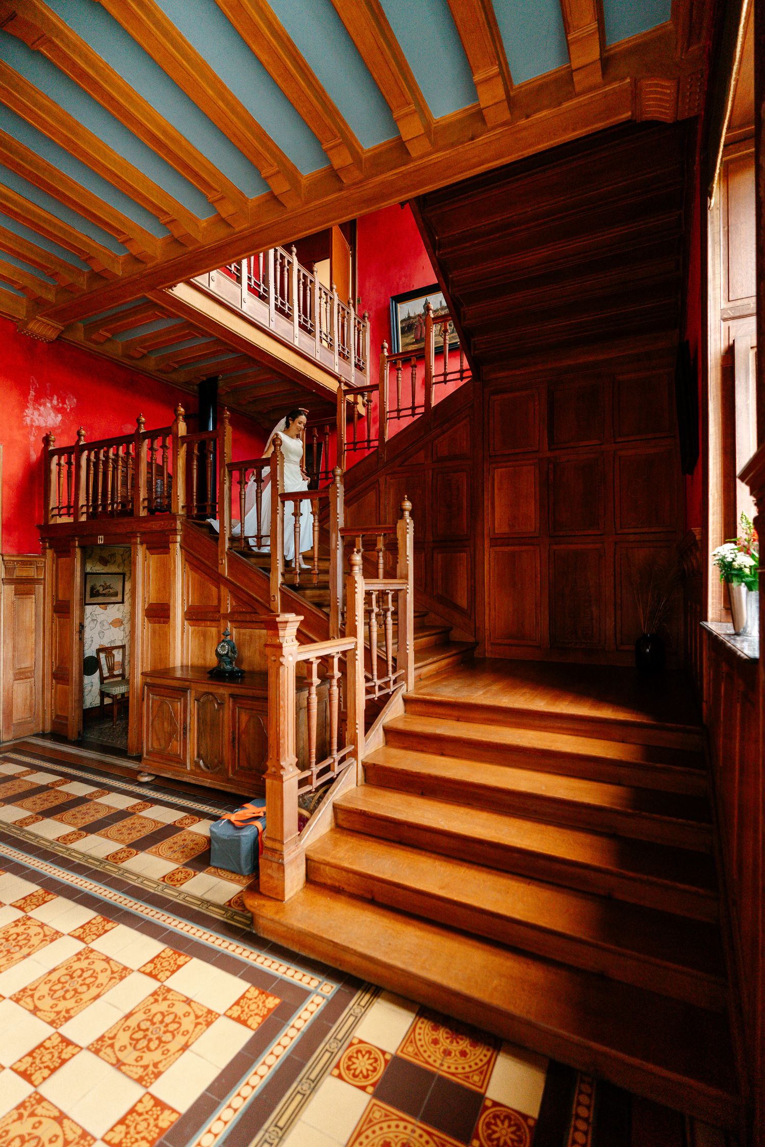 Ornate wooden staircase with decorative tile flooring and warm lighting showcases Victorian-era architectural details.