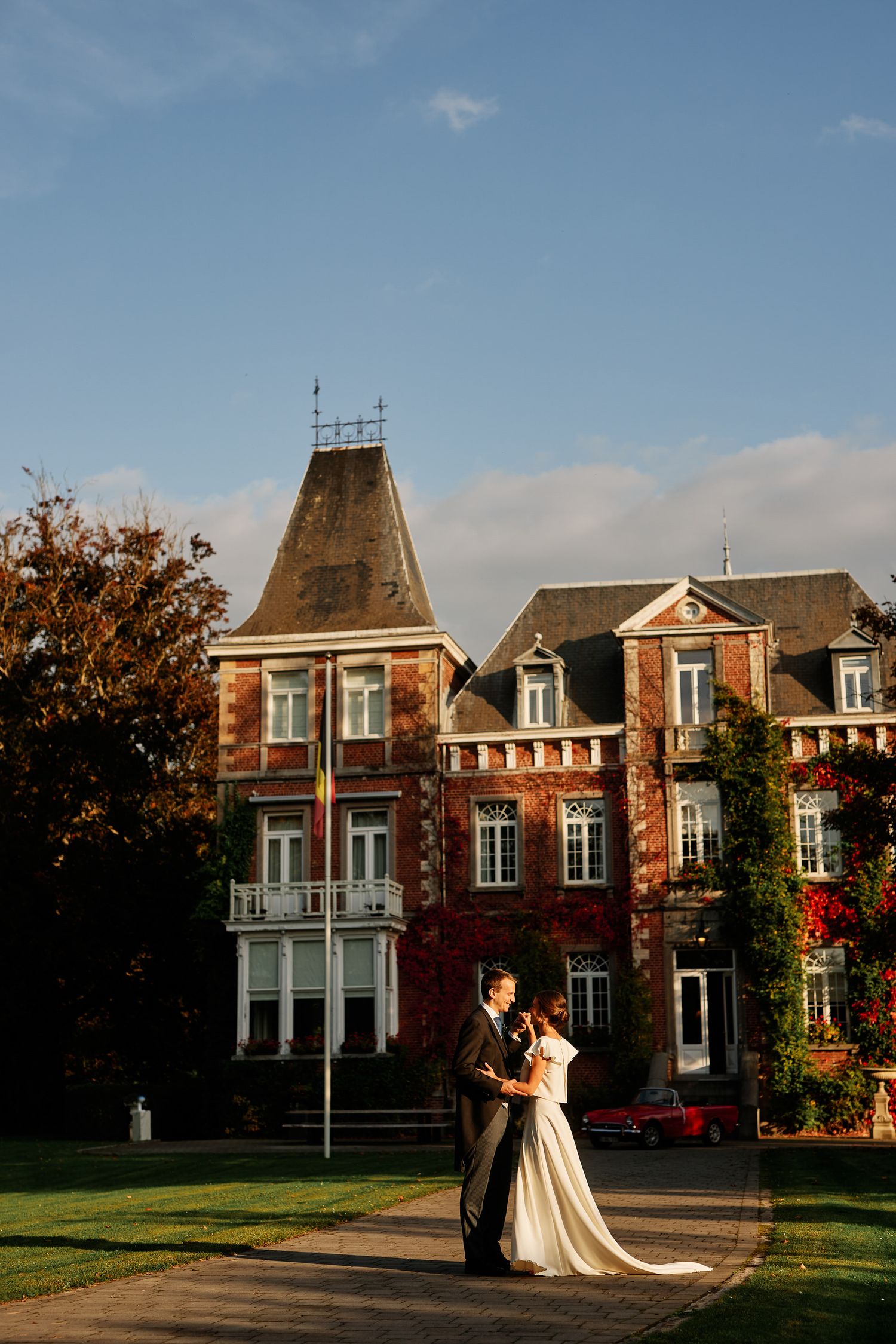 Historic red brick mansion with white trim and bay windows shown at different angles during sunset golden hour.