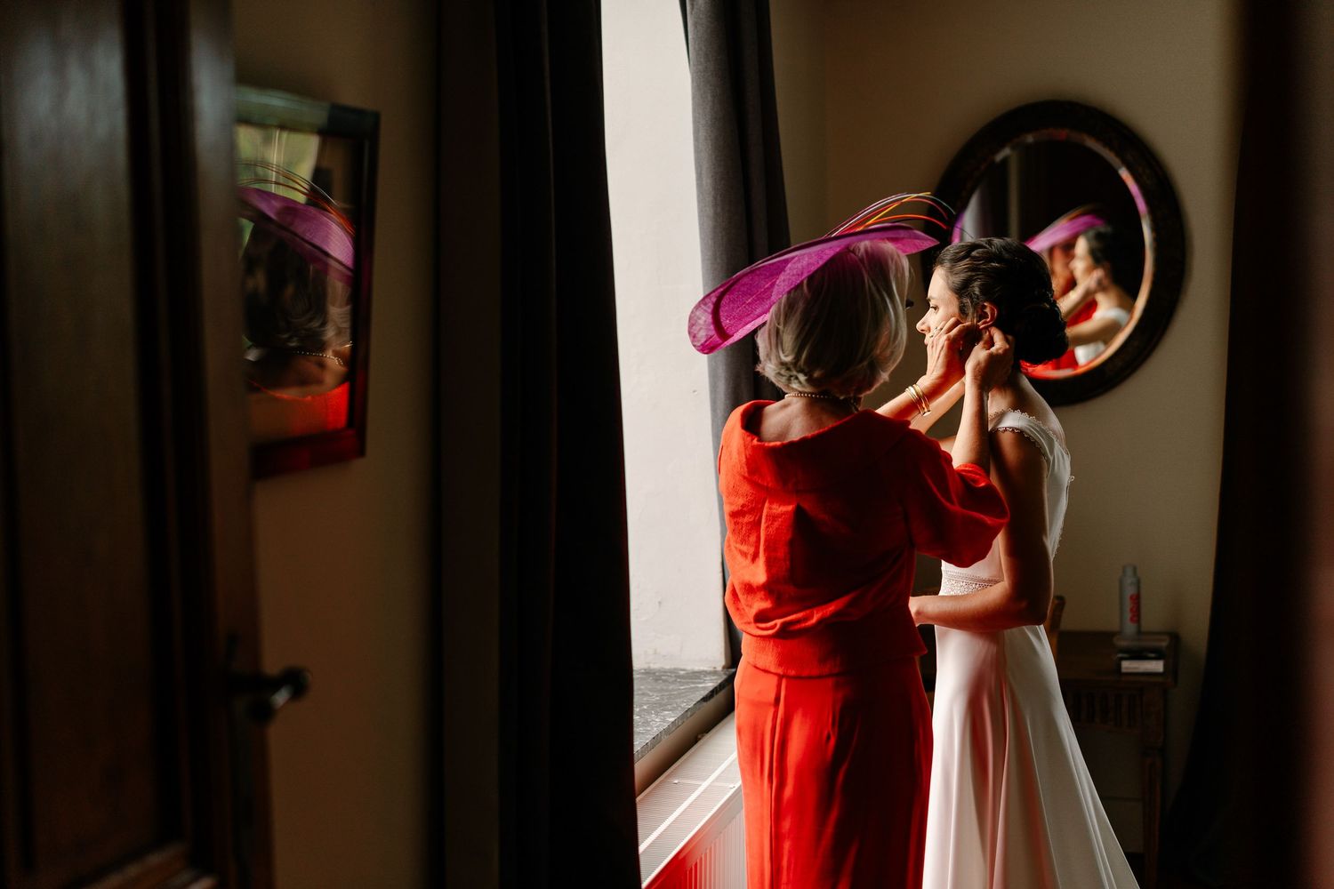 A couple in formal attire dances together in a dimly lit room with dramatic lighting and shadows.