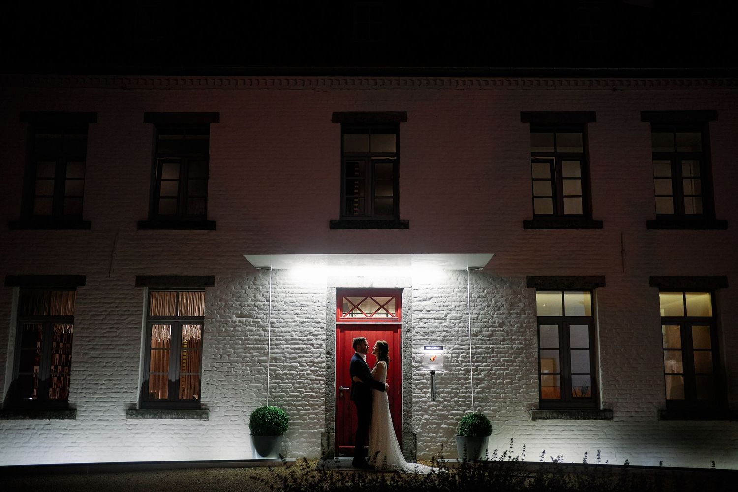 Nighttime exterior view of illuminated white stone building facades with dark windows in a row.