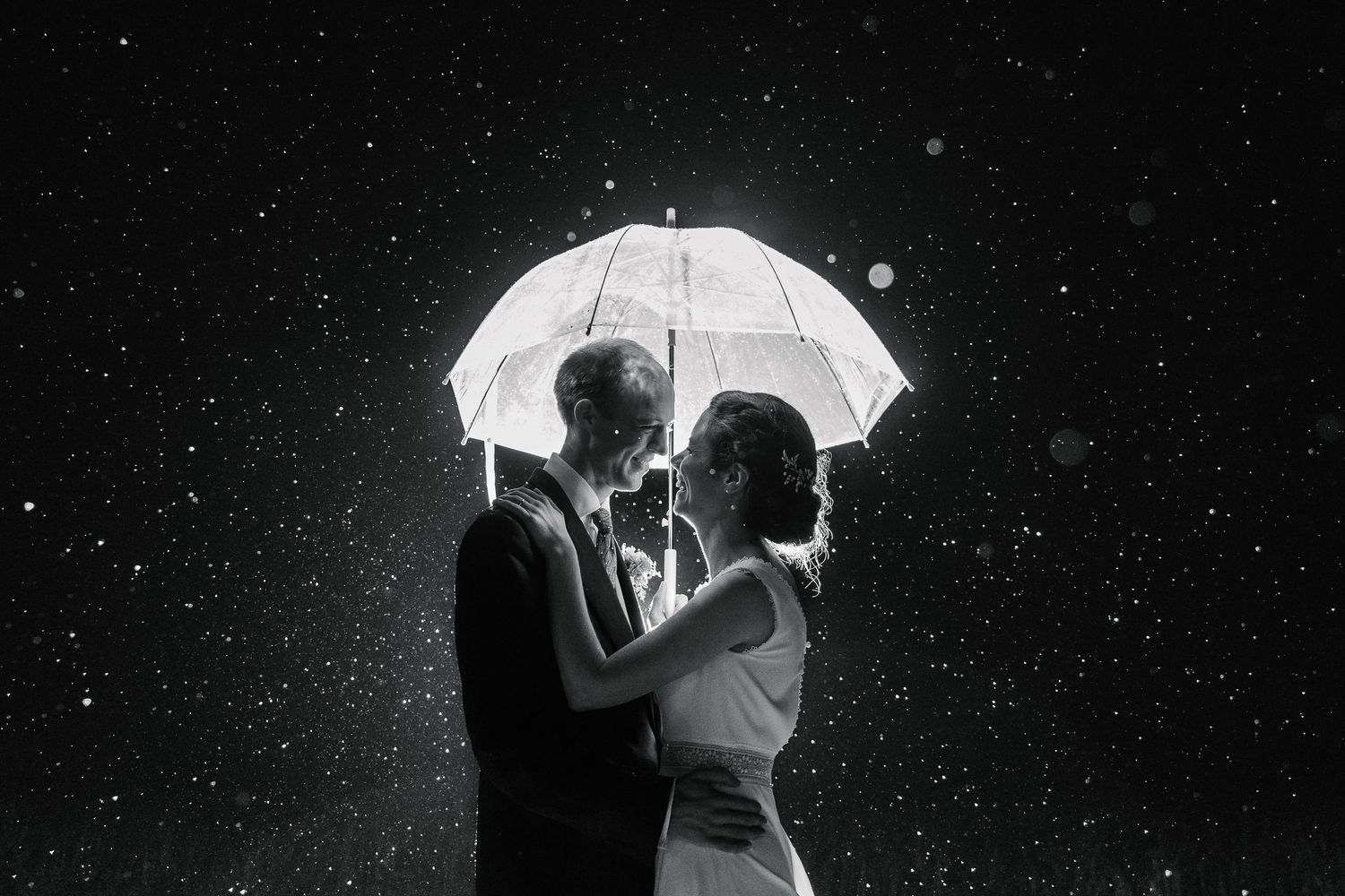 A silhouette holds a white umbrella against a dark starry sky creating a dreamy nighttime scene.