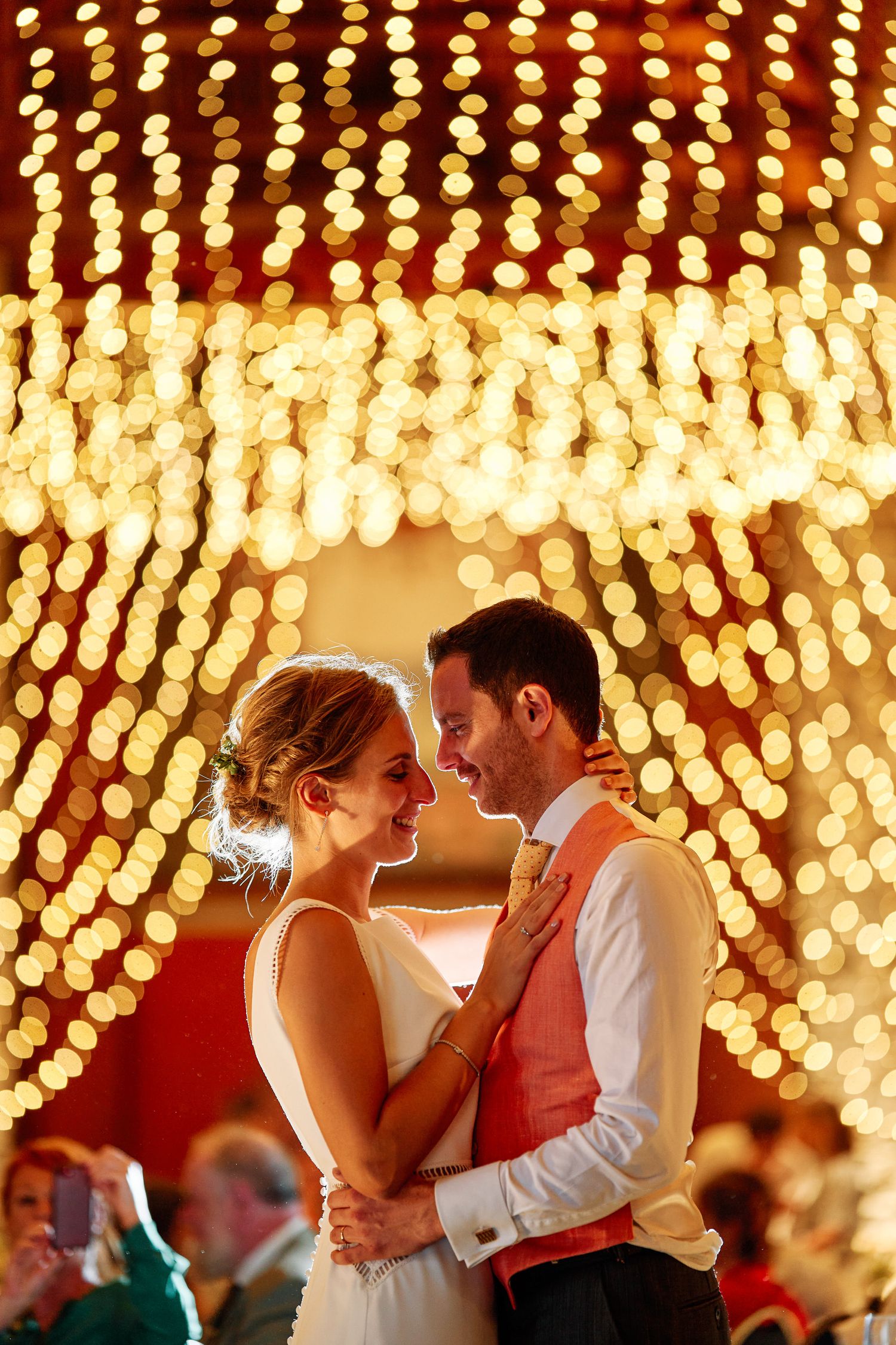 A romantic couple dances under a magical canopy of twinkling string lights at an evening reception.