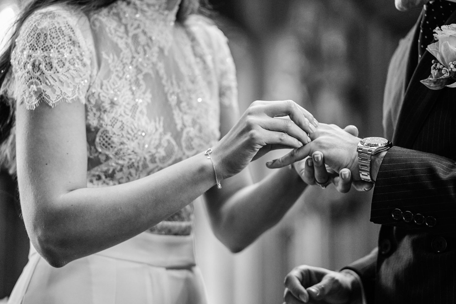 A collection of black and white wedding photos showing hands exchanging rings during a ceremony.
