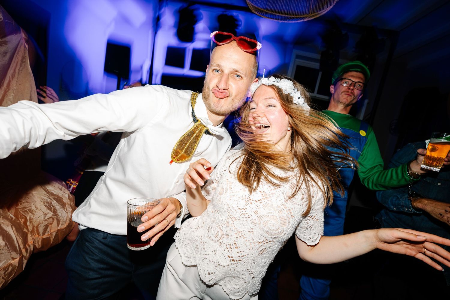 Group of people dancing and having fun at a nightclub with colorful lighting and energetic atmosphere.