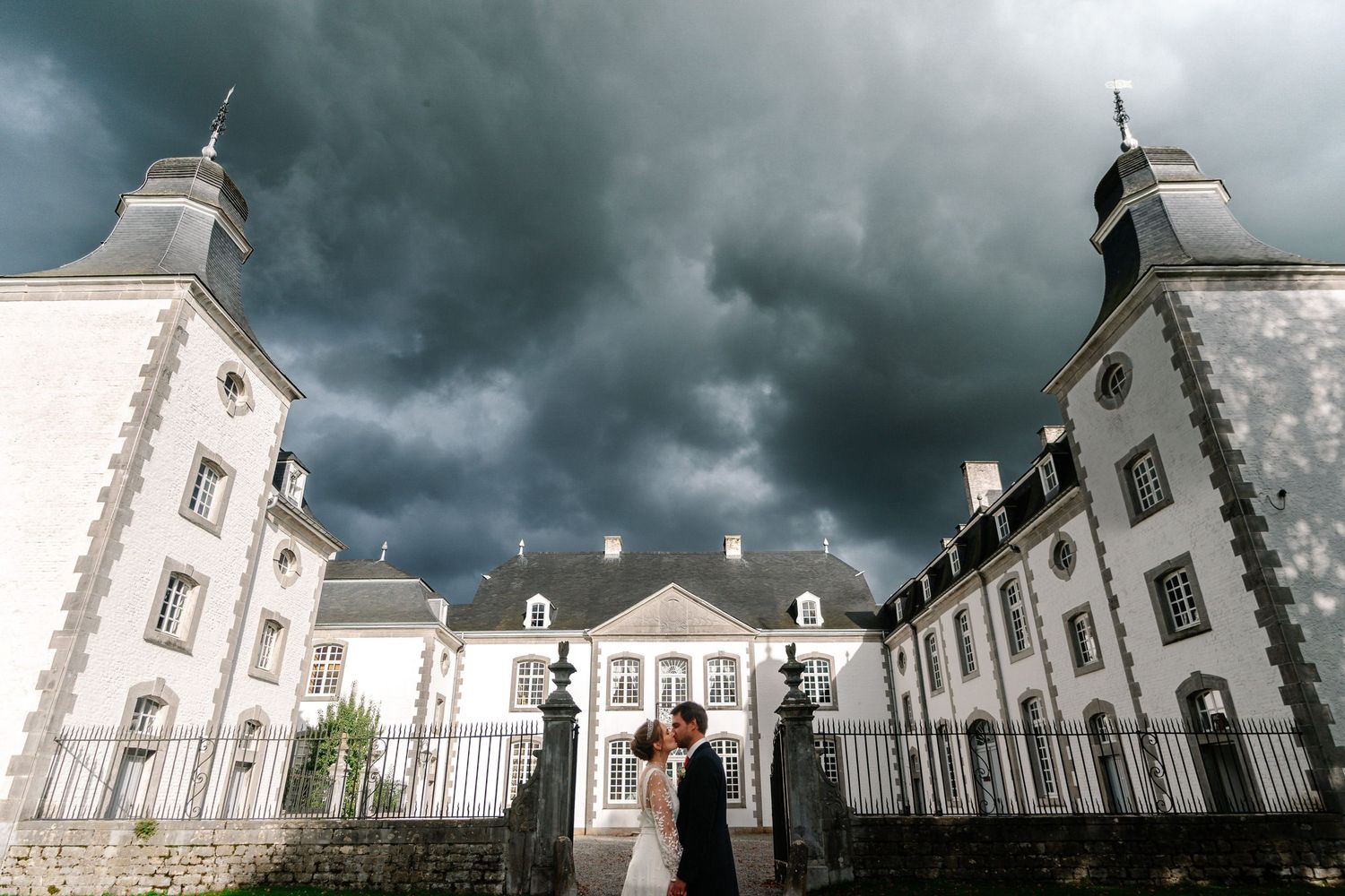 Historic white mansion under dramatic stormy sky with gothic architecture.