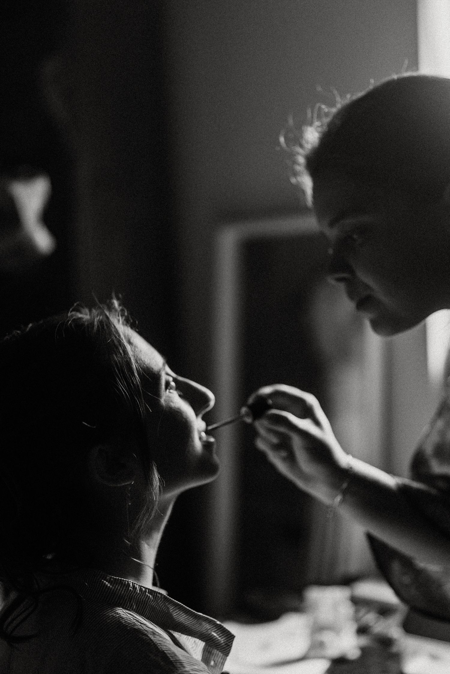 Black and white photos show makeup being applied in dramatic lighting and shadows.