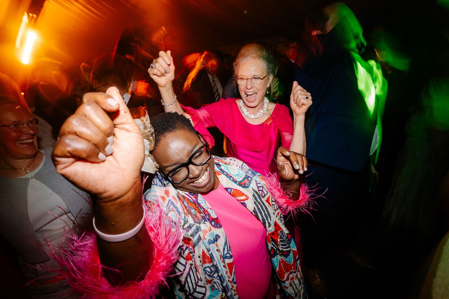 People dancing and having fun at a nightclub with colorful lighting and energetic atmosphere.