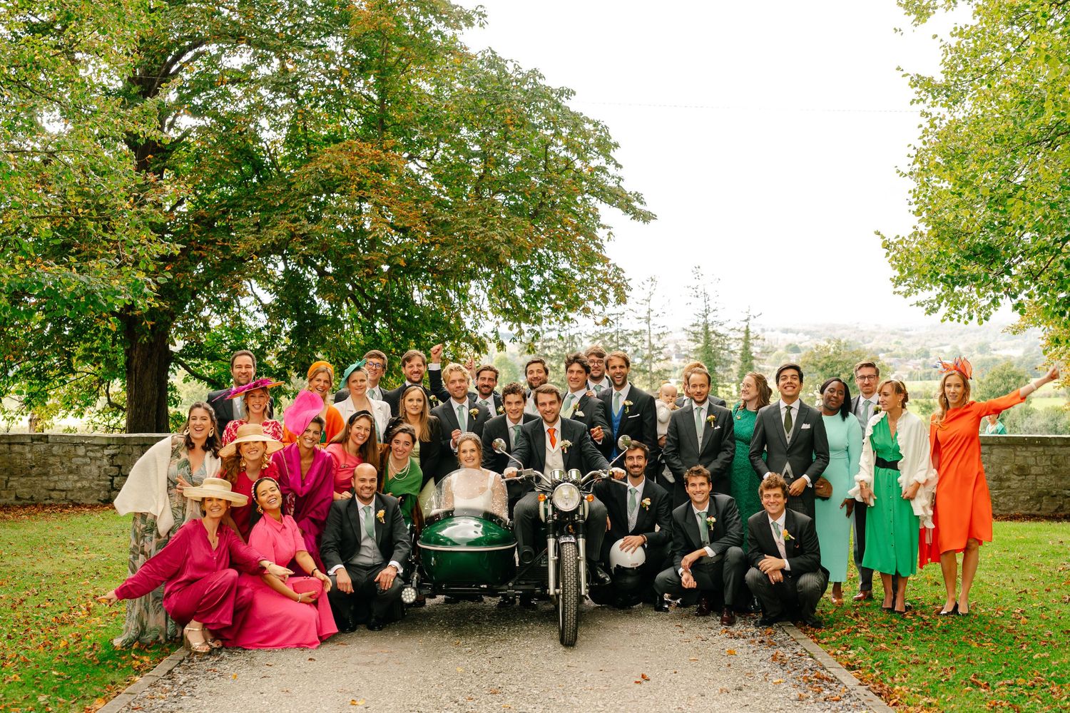 A panoramic collage of wedding party group photos taken outdoors with vibrant greenery and colorful attire.