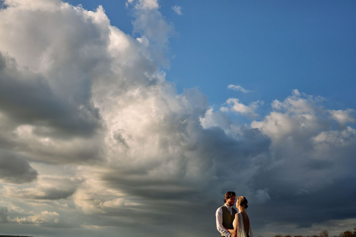 Dramatic cloudy sunset sky over beach with silhouettes creating a romantic coastal atmosphere.