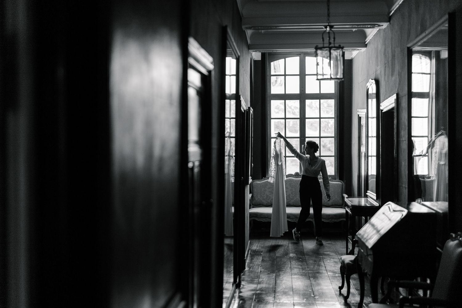A dramatic black and white architectural photograph showing a long corridor with windows casting dramatic shadows.