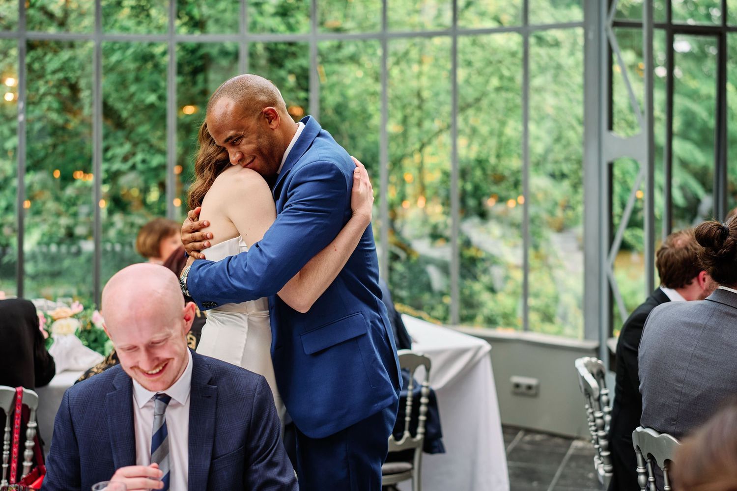 A couple shares a romantic dance moment in a sunlit greenhouse setting during their wedding celebration.