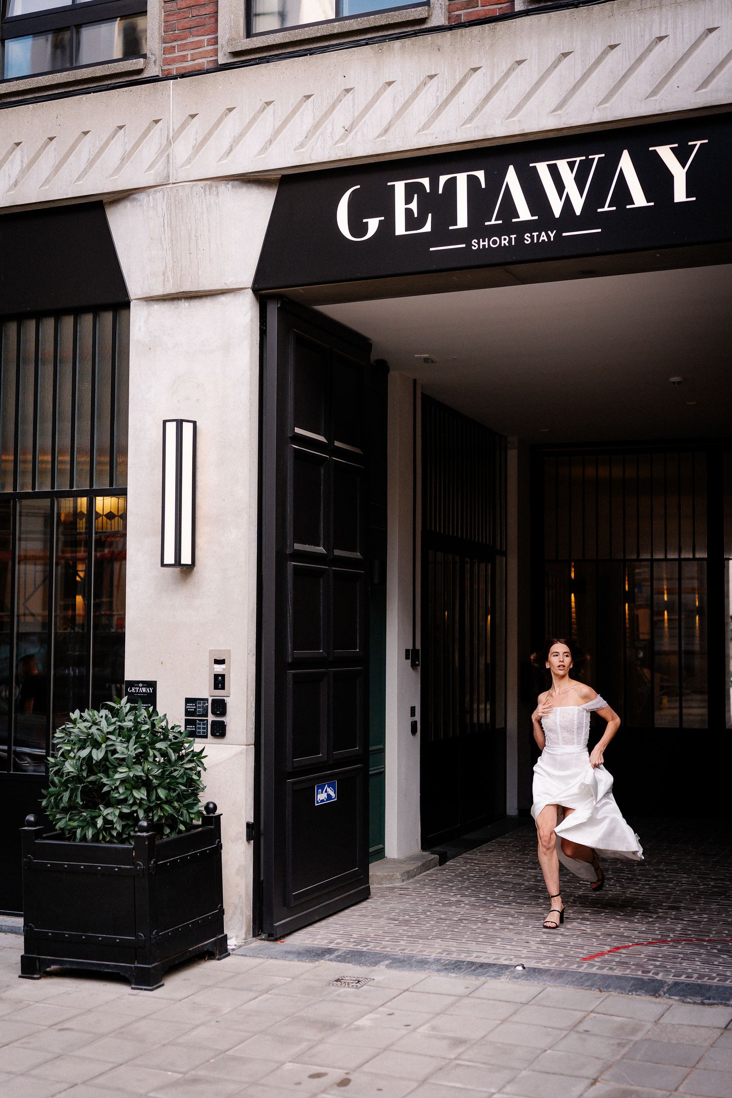 A series of storefront photos showing the entrance to a boutique hotel called Getaway with black framed windows and planters.