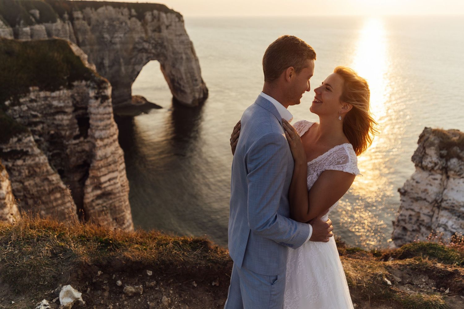A romantic wedding photoshoot at sunset near dramatic coastal cliffs and natural stone arches.