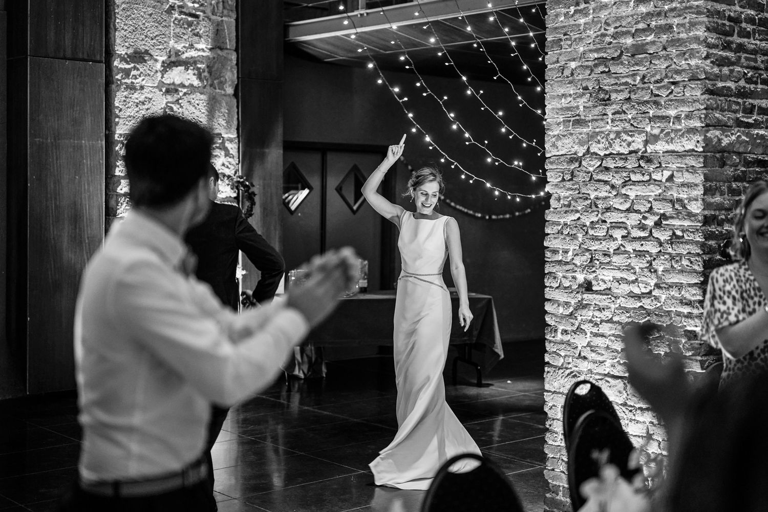 Black and white photo series showing couples dancing and embracing at a wedding reception with string lights in background.
