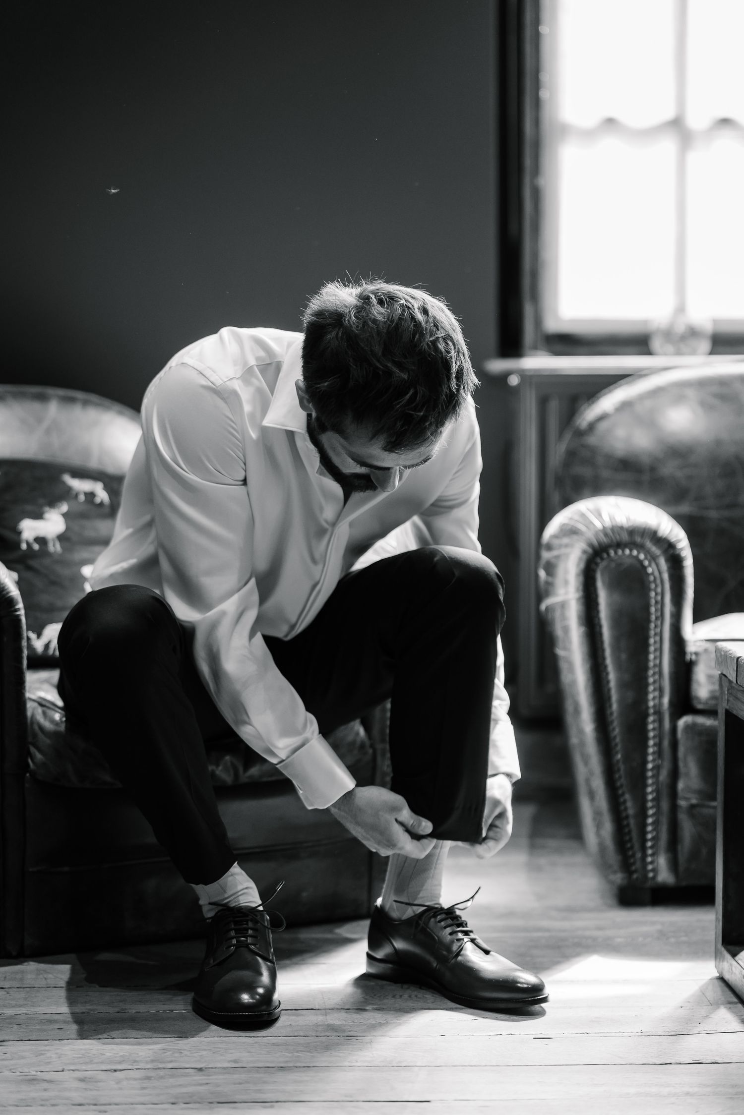 Black and white photo sequence showing someone tying dress shoes on a hardwood floor.