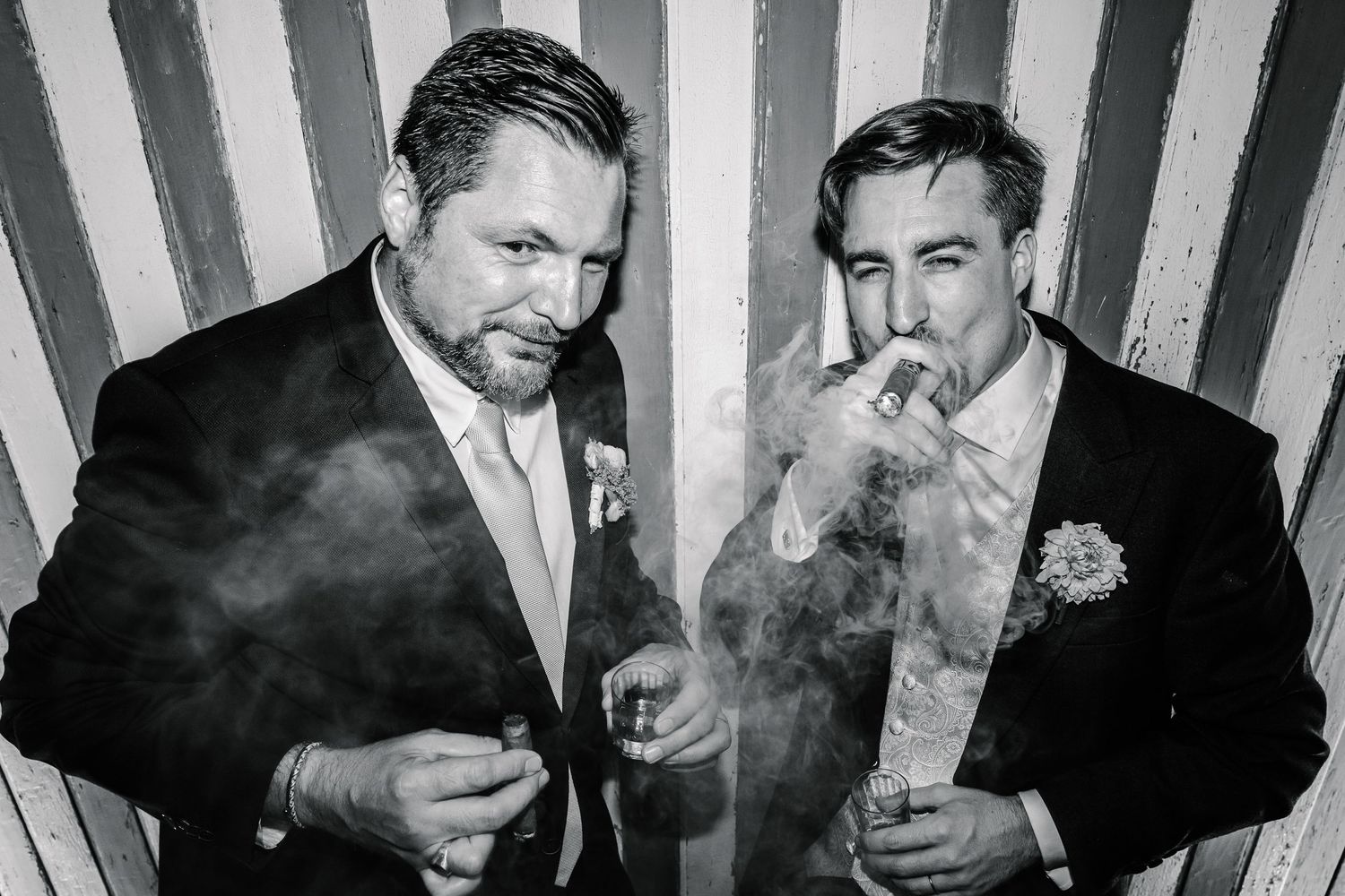 A black and white photograph shows people smoking cigarettes in a striped background setting.