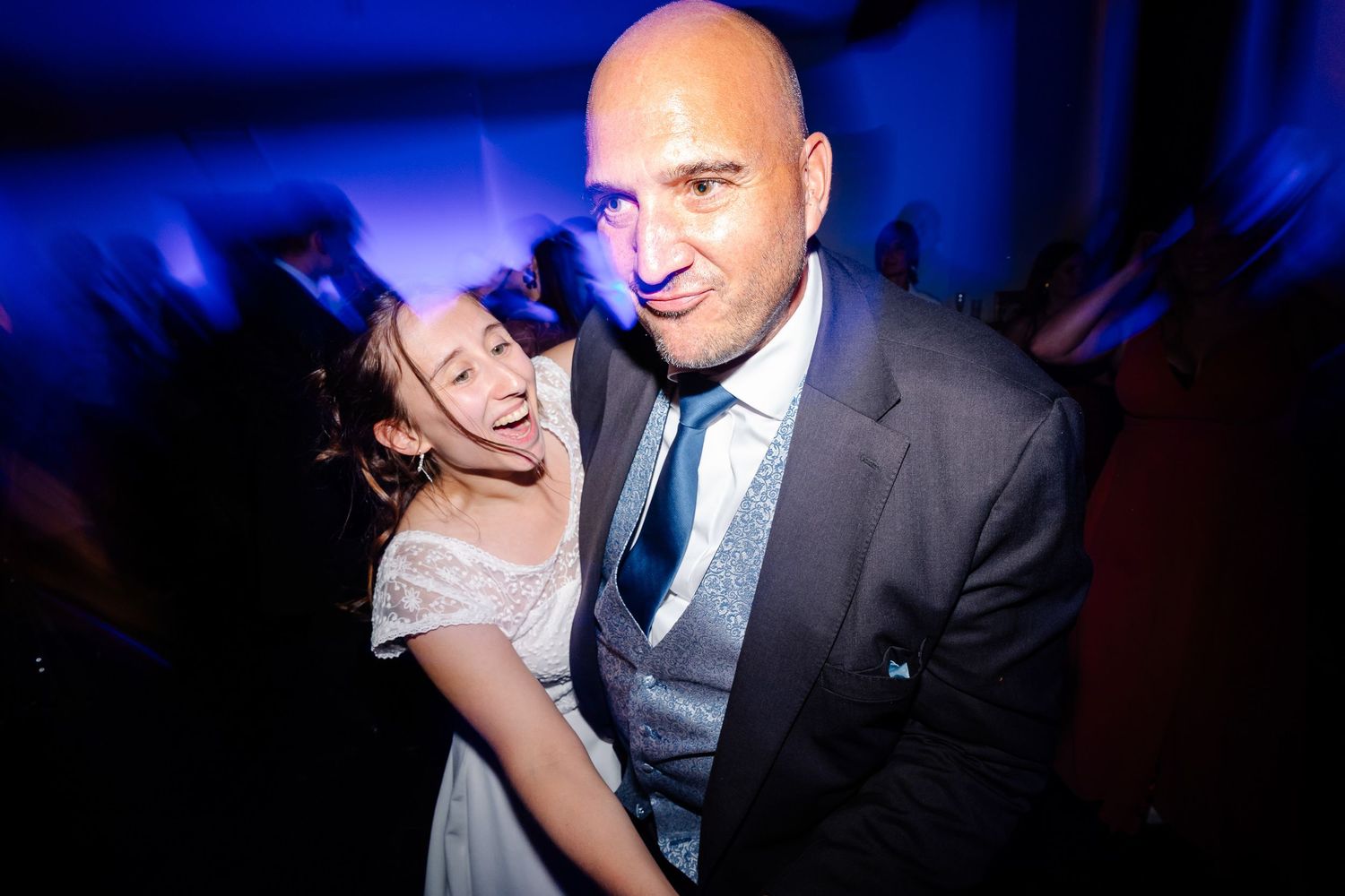 People dancing together in a dark nightclub setting with blue lighting effects.