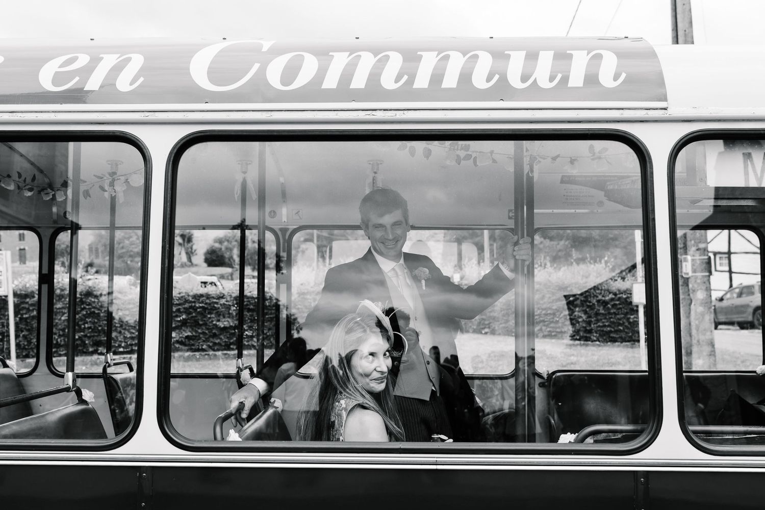 Vintage black and white photograph showing passengers looking out windows of a classic bus or train car.