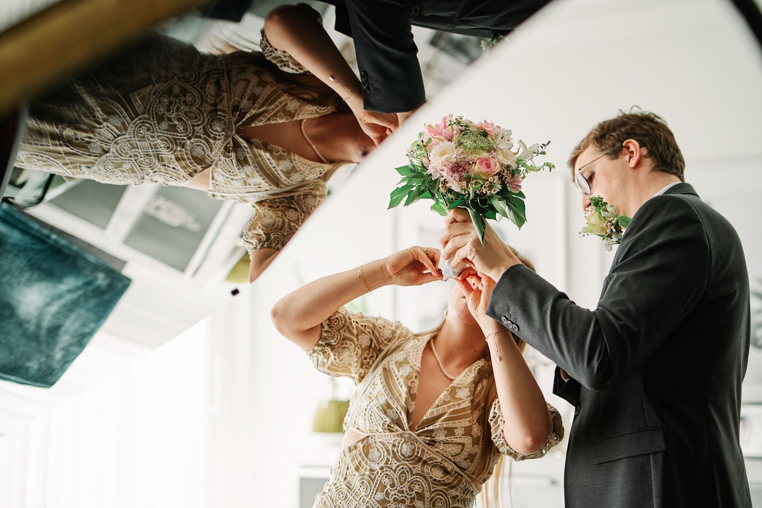 A couple in formal wedding attire shares an intimate moment during their wedding ceremony in a sunlit venue.
