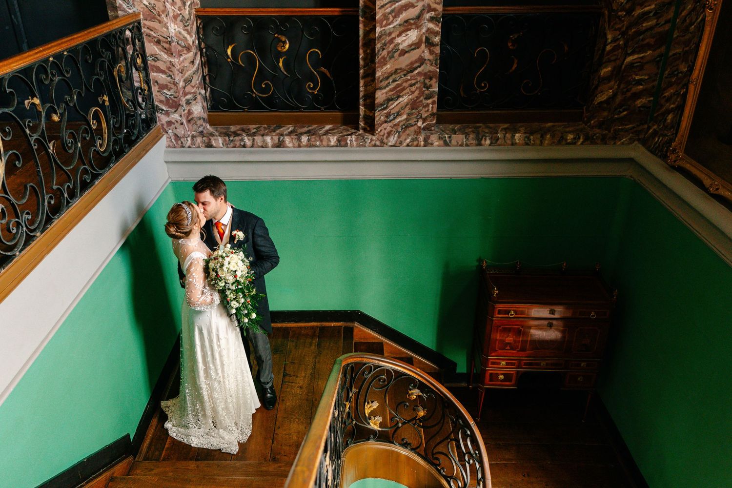 A wedding couple stands at the altar in an ornate church with green walls and elegant architectural details.