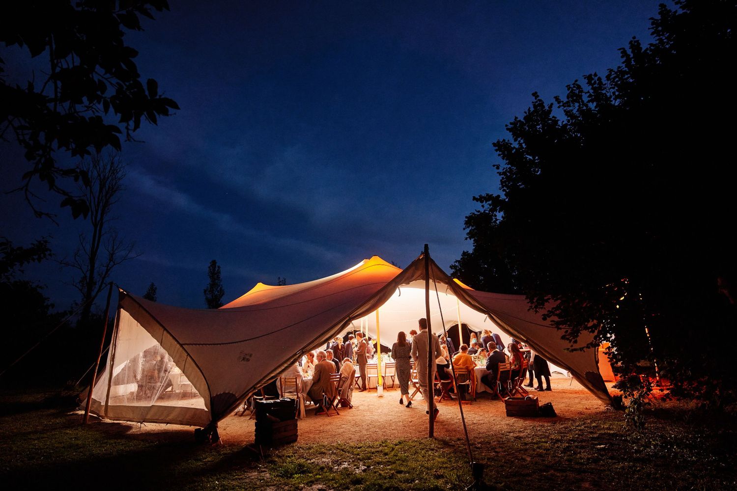 A series of illuminated white event tents at dusk creating a magical outdoor venue atmosphere.
